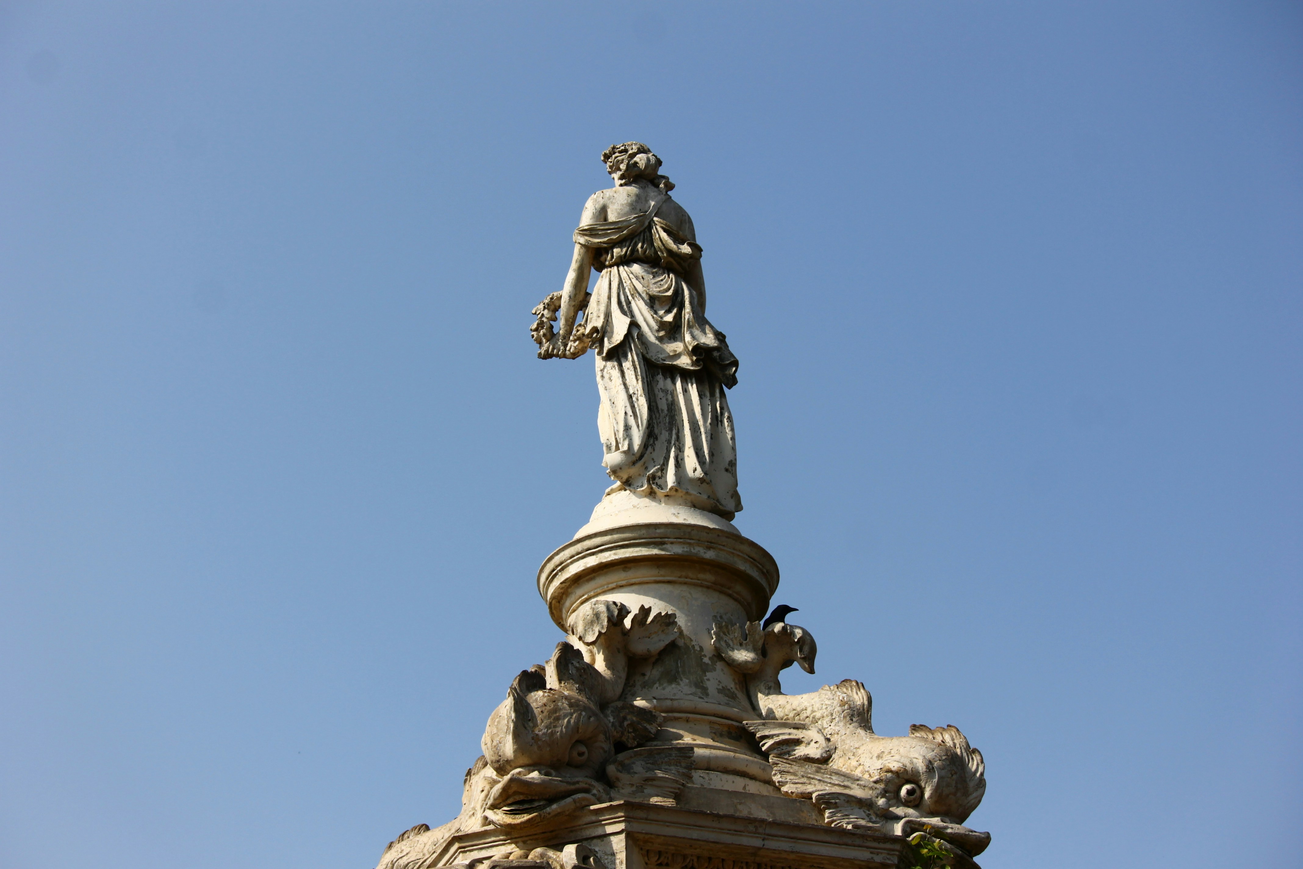 A stone statue of a woman against a blue sky.