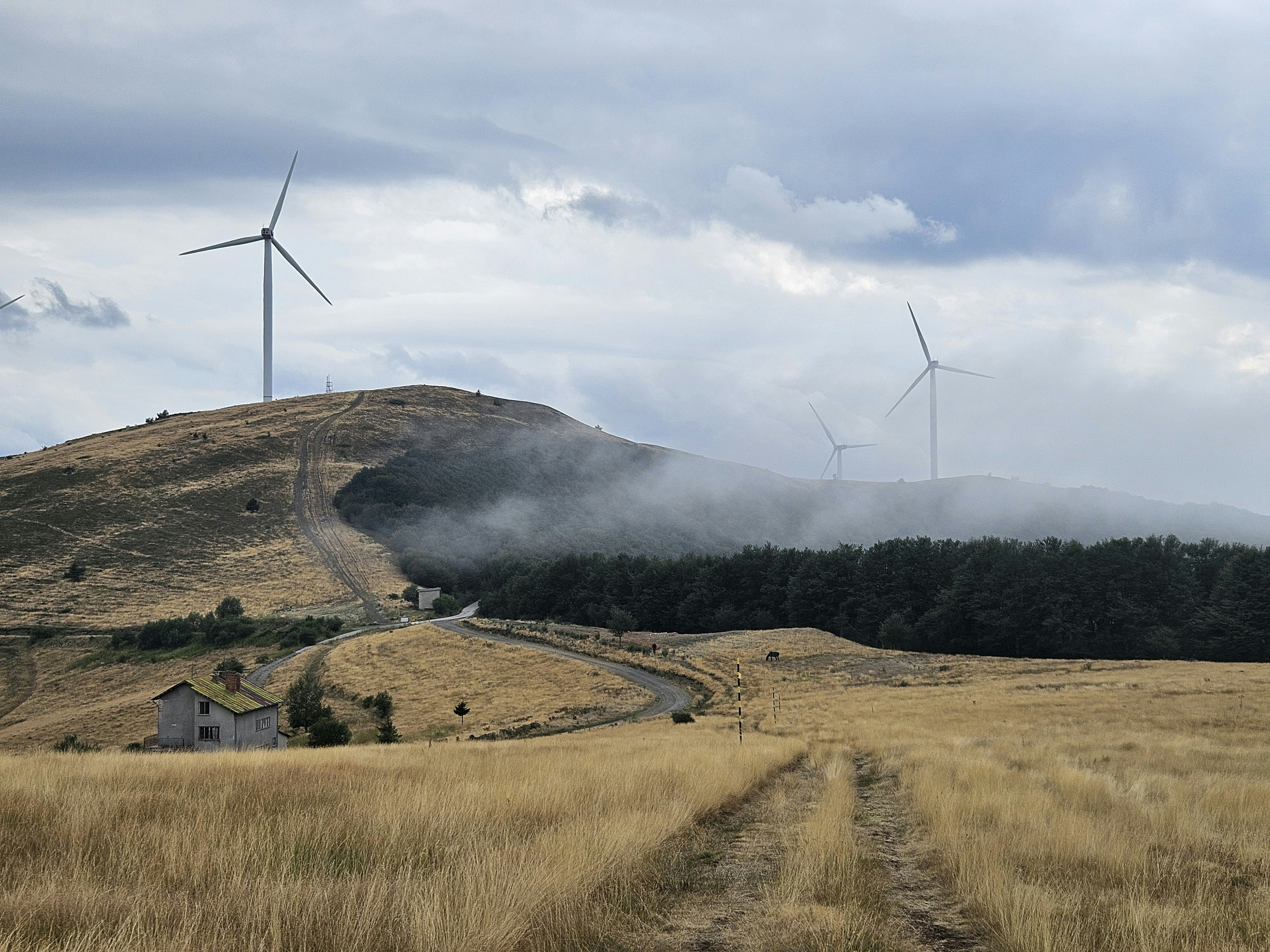 Wind turbines on a grassy hill with clouds