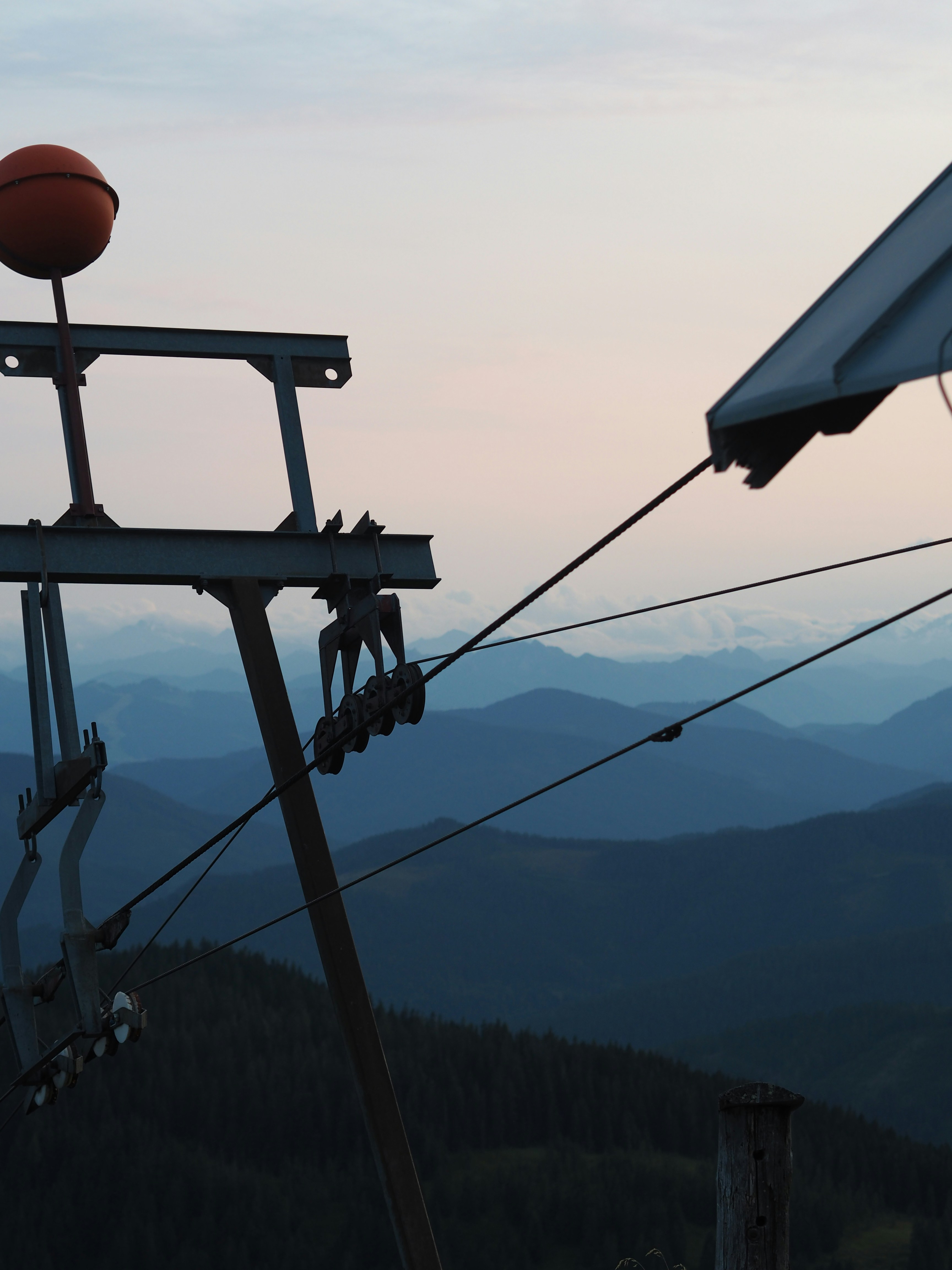 Ski lift machinery against hazy blue mountain layers.
