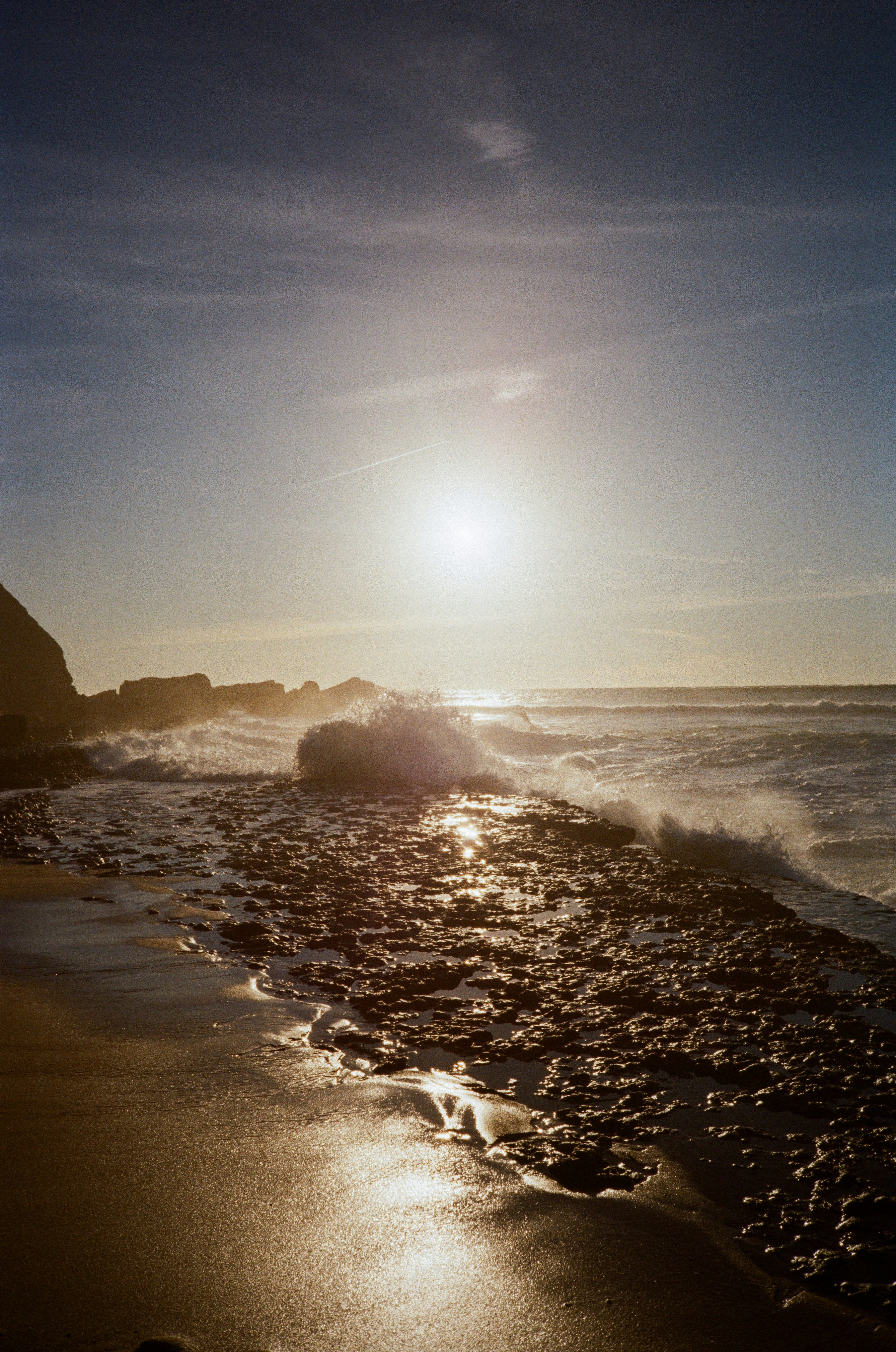Wellen brechen bei Sonnenuntergang an einer felsigen Küste
