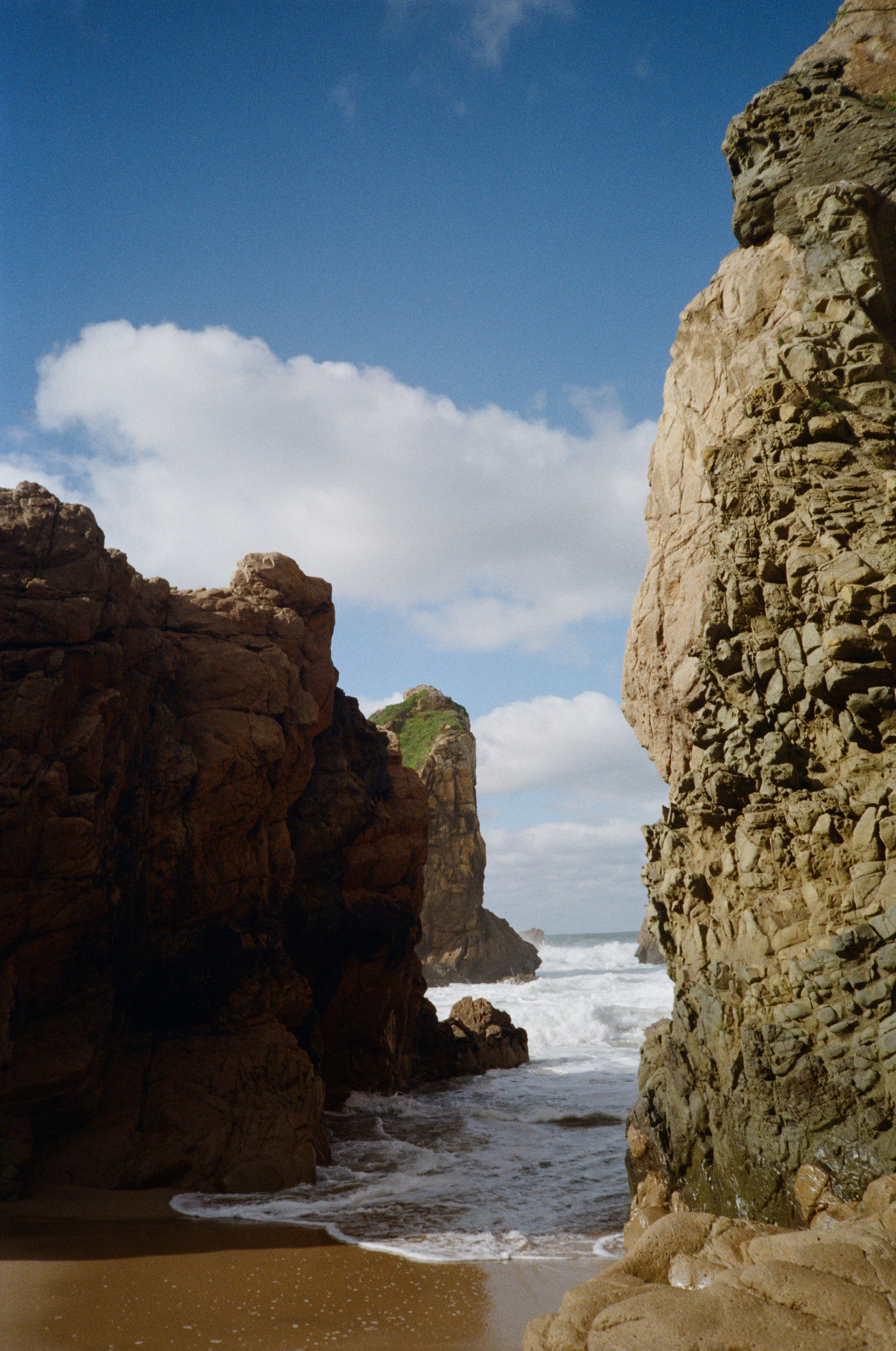 Wellen, die unter einem bewölkten Himmel an einen felsigen Strand schlagen.