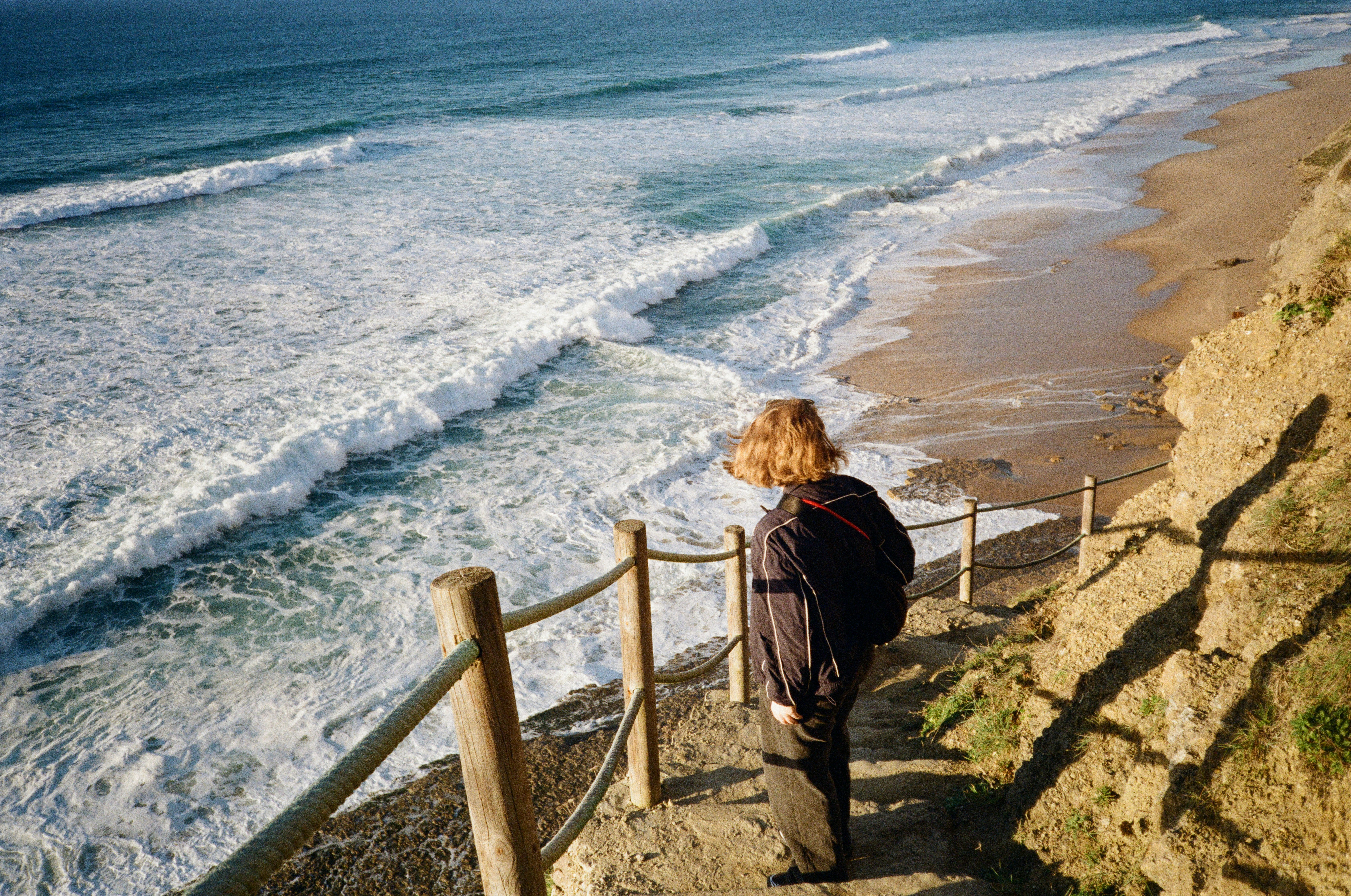 Person, die vom Klippenpfad aus auf die Wellen des Ozeans schaut