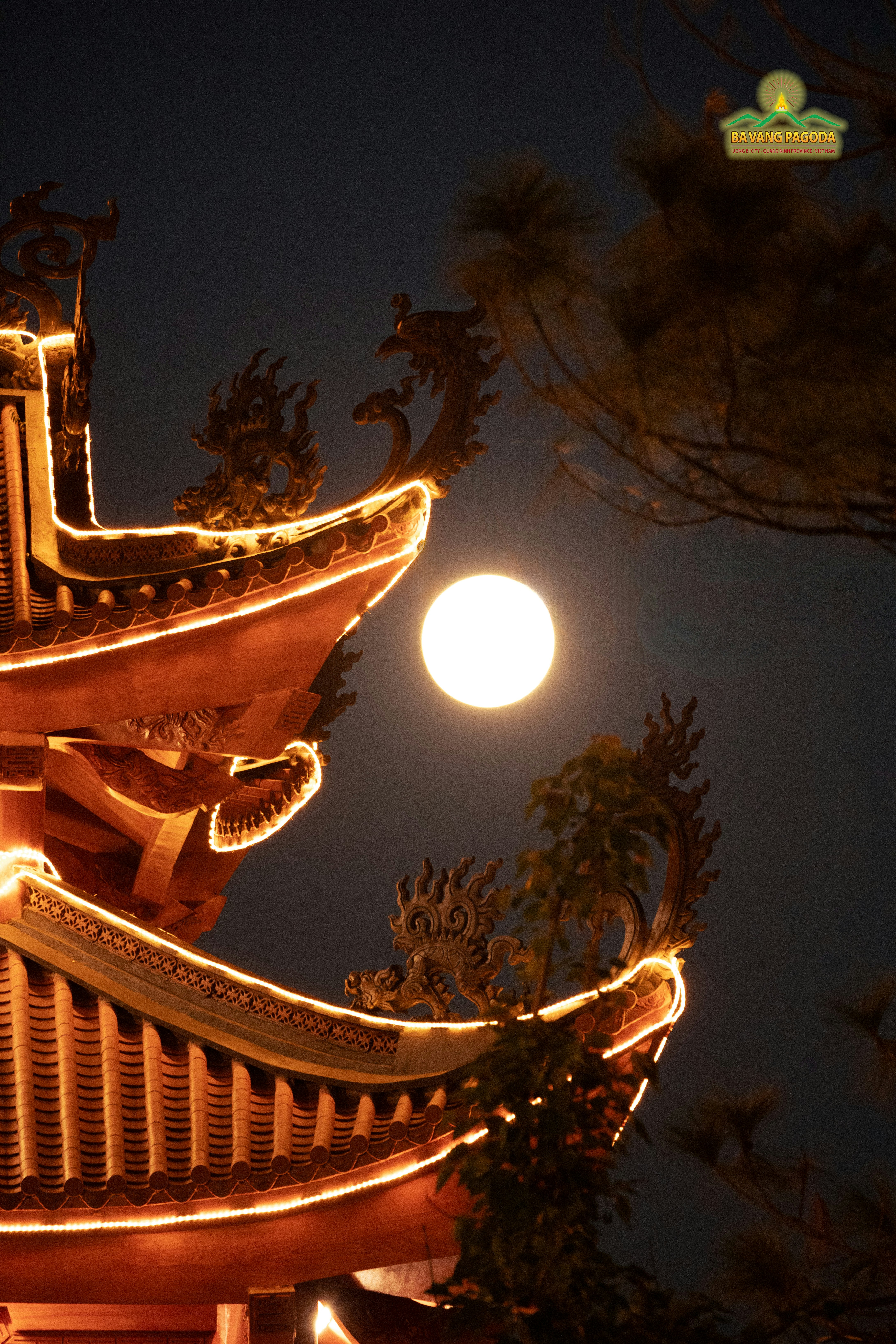 Full moon shines over illuminated temple roofs at night