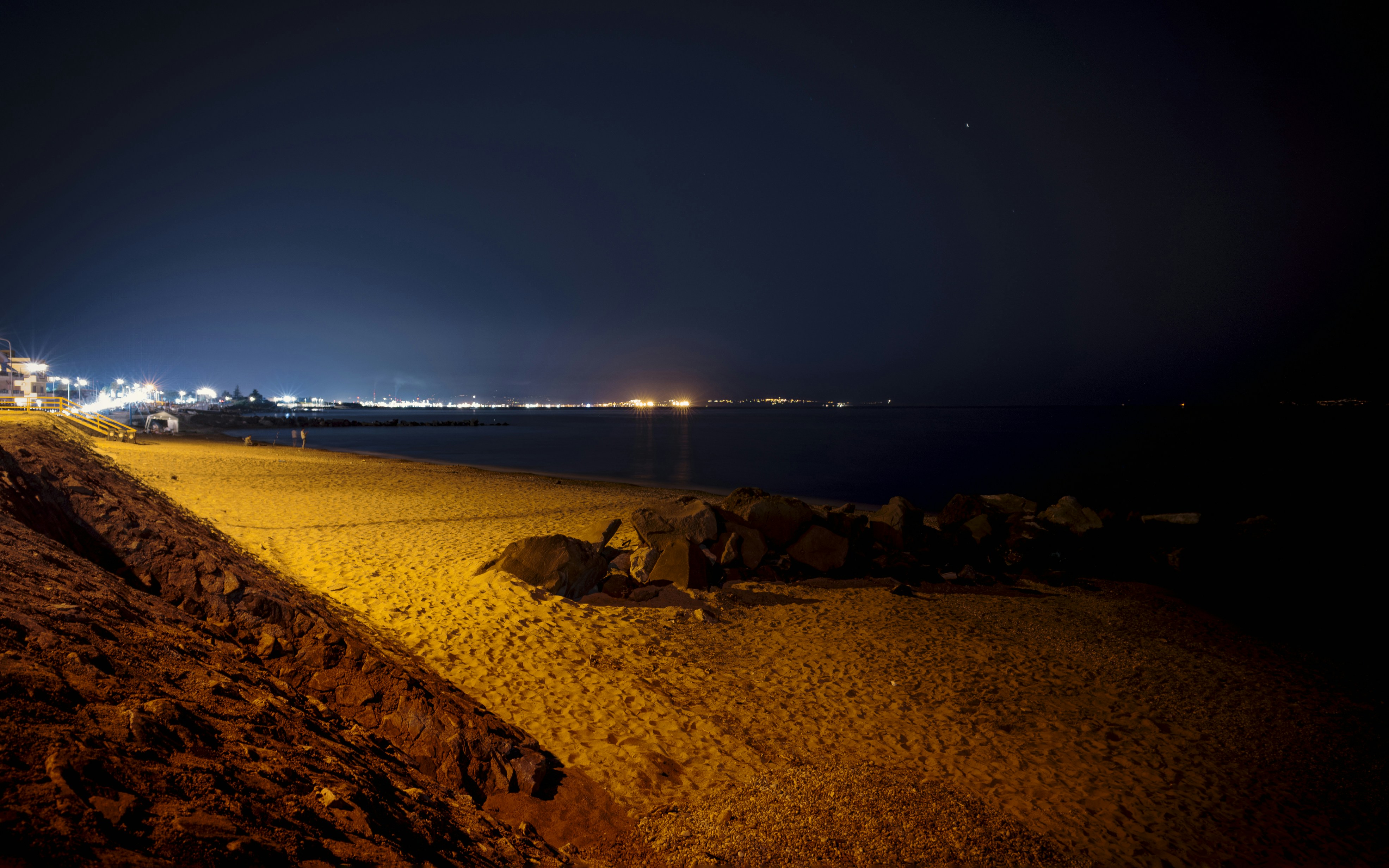 Beach at night with distant city lights