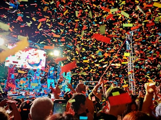 Crowd celebrating with colorful confetti at a concert.
