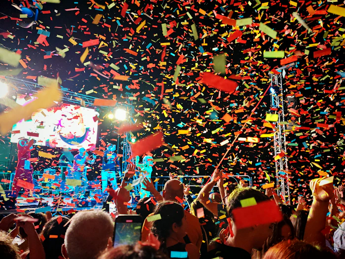 A crowd celebrating under falling confetti at a festival