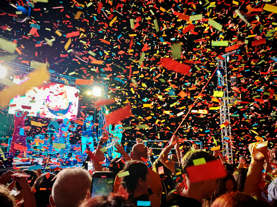 A crowd celebrating under falling confetti at a festival stage