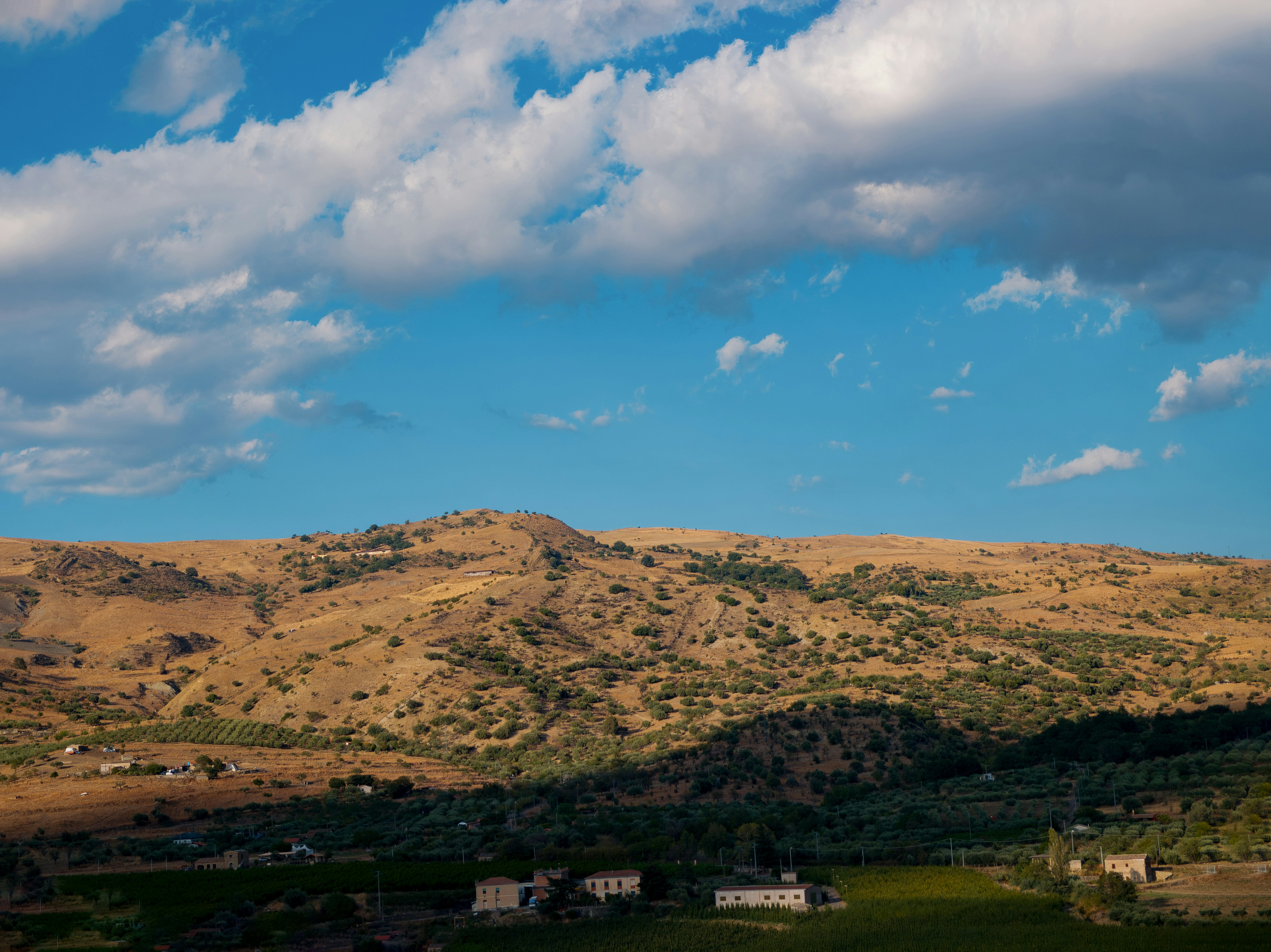 Rolling hills under a cloudy blue sky