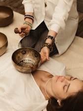 Person playing singing bowls on a person lying down