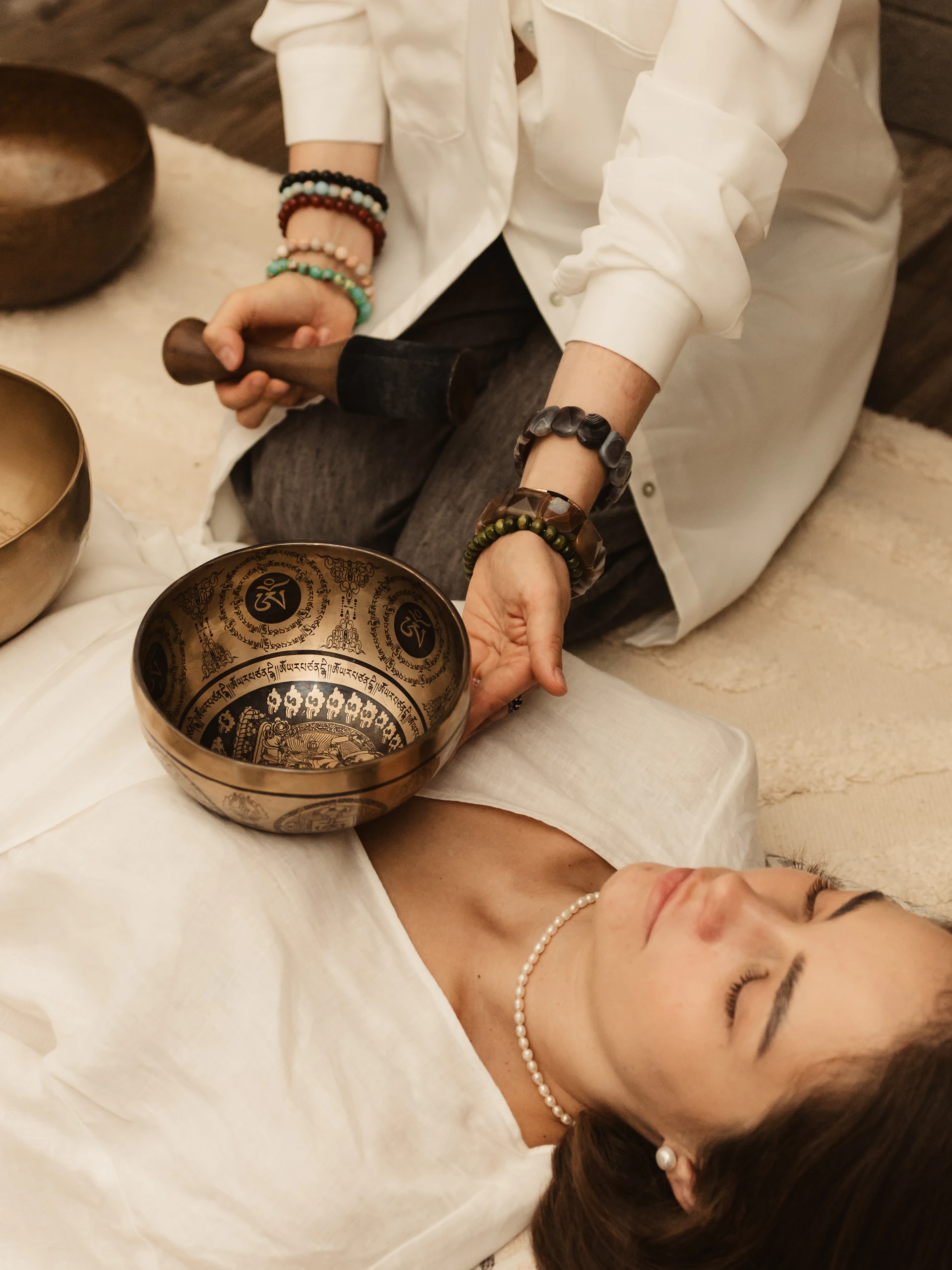 Person playing singing bowls on a person lying down
