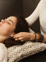 Therapist gently touching woman's ear during treatment.