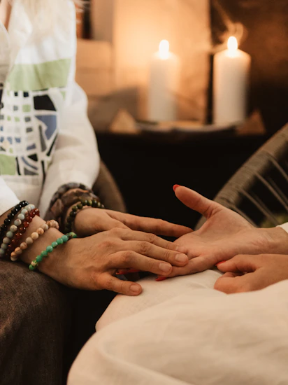 Hands being read by a fortune teller with candles.