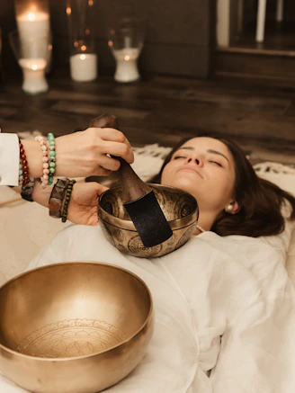 Woman receiving sound healing with singing bowls.