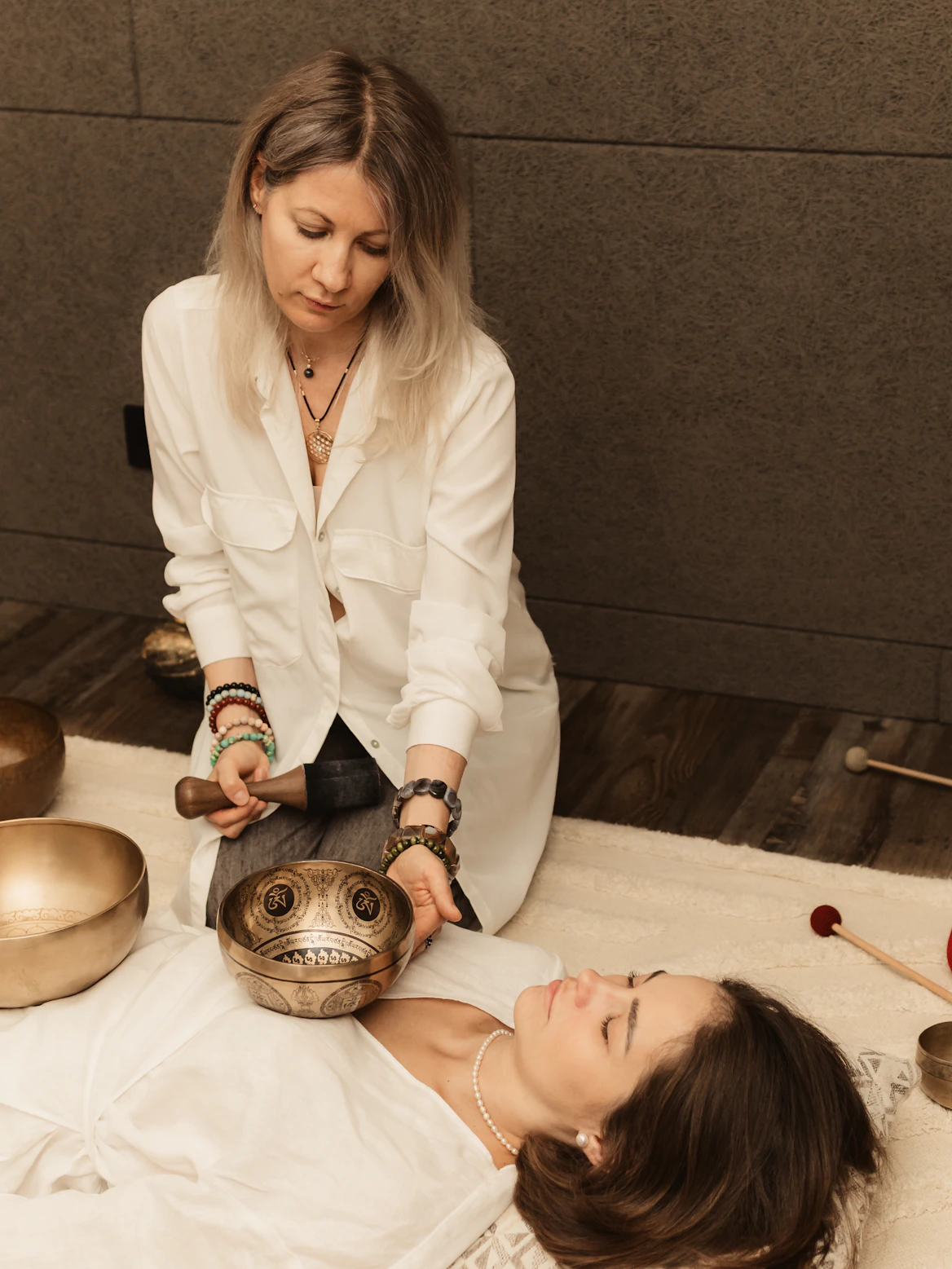 Woman receiving sound healing with singing bowls.