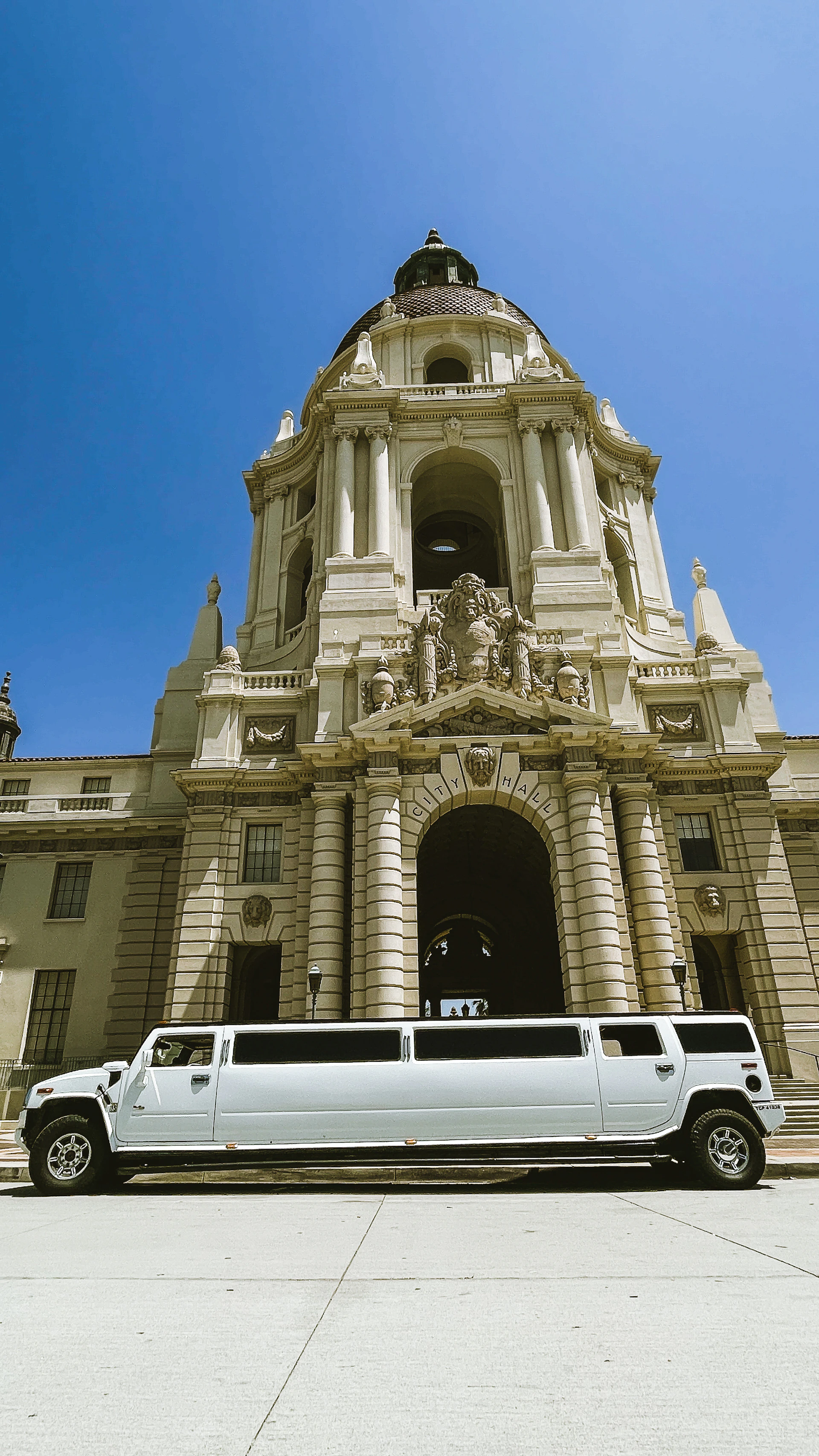 White limousine parked in front of a grand building.