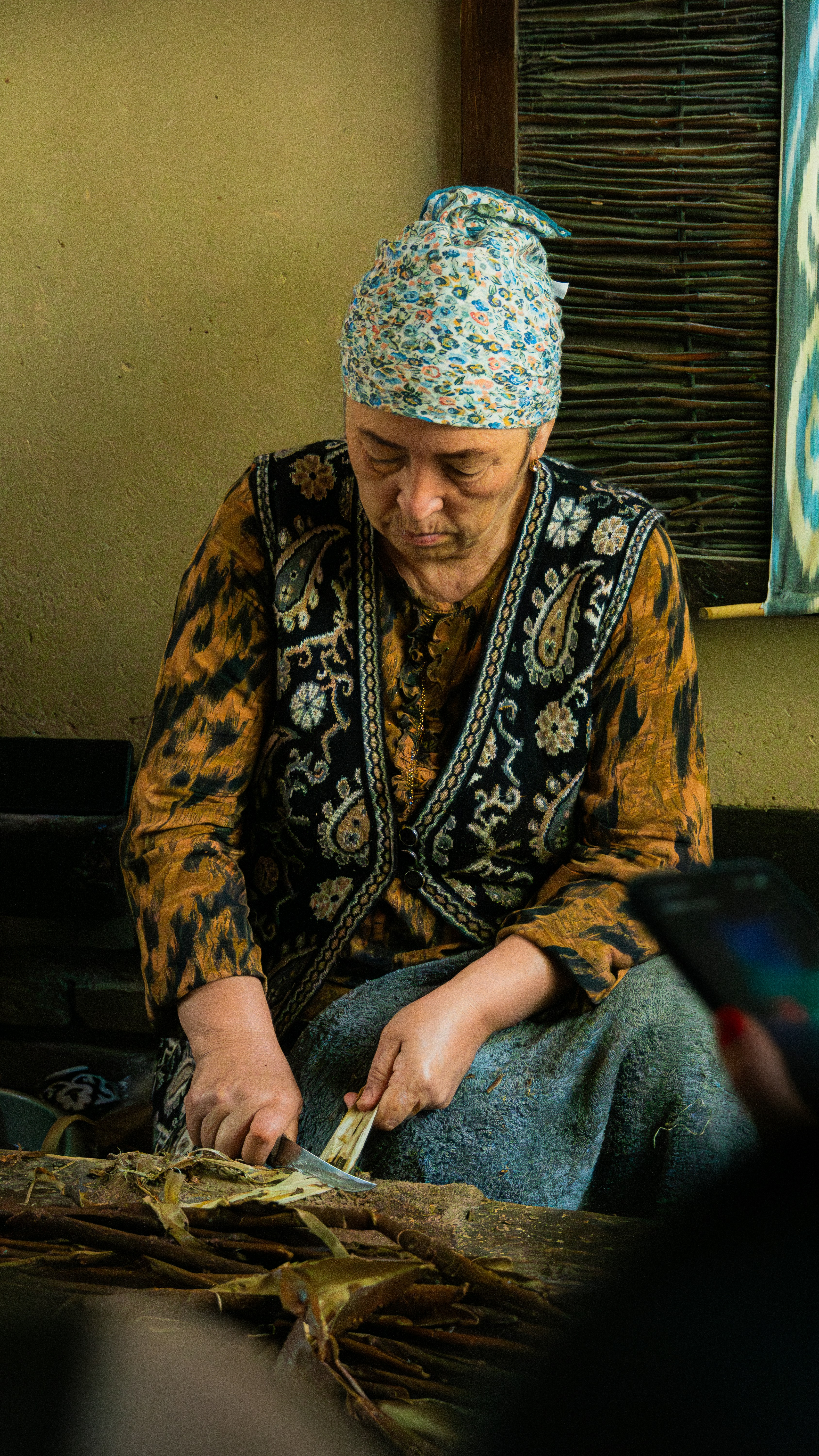 Woman in traditional clothing working with reeds and crafts. Photo by Tommaso Nava on Unsplash.