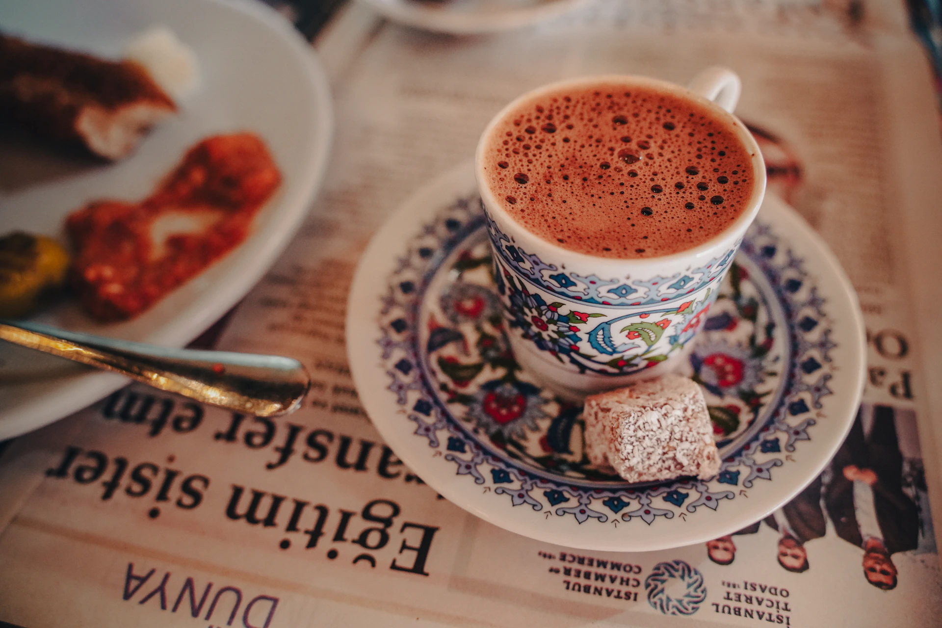 A cup of turkish coffee with a delight cube of turkish delight.