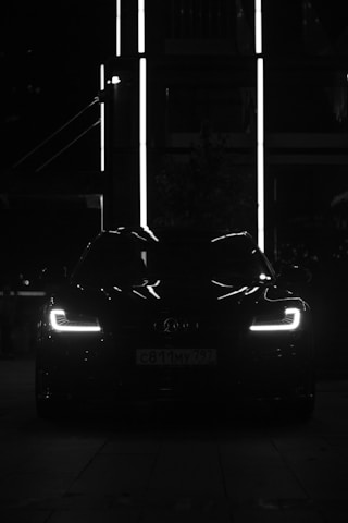 Black car with illuminated headlights at night