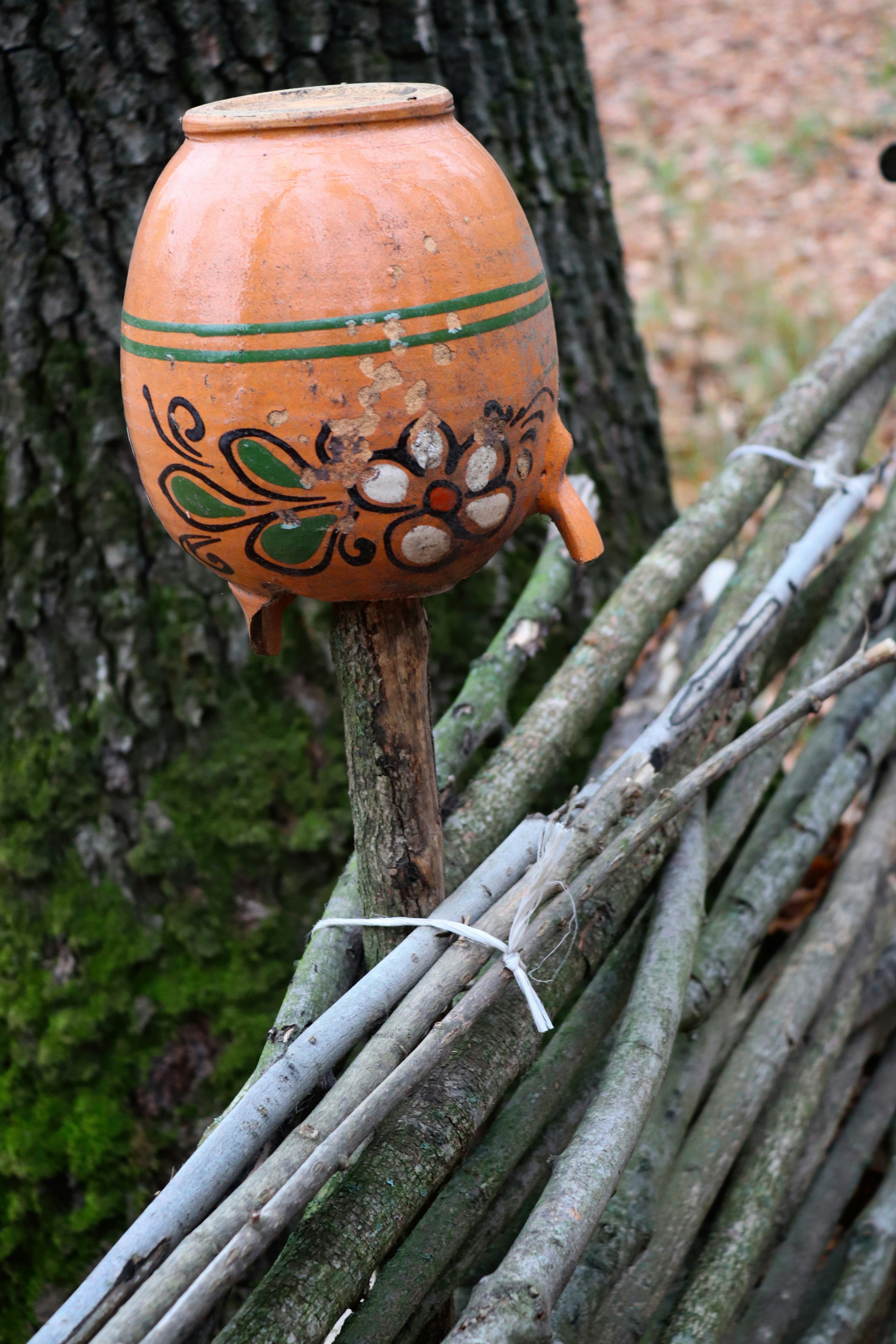 Clay jug with flower design on wooden stand