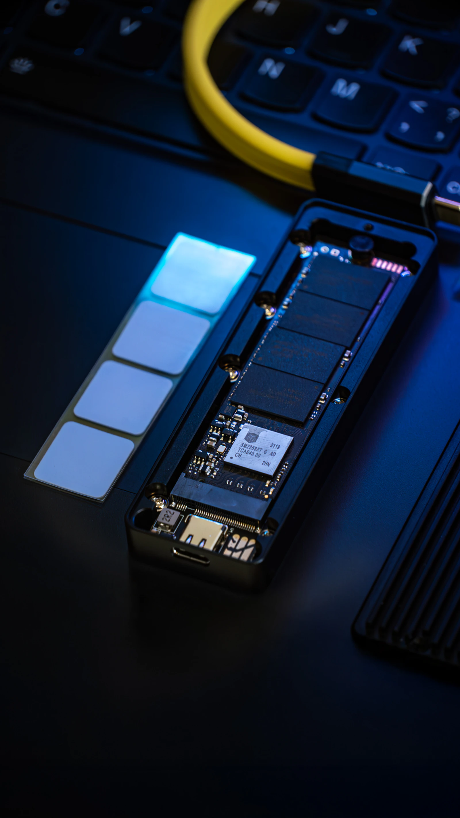 Disassembled solid-state drive showing NAND memory chips and the green circuit board of SSD storage hardware