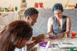 Three women painting and crafting at a table.