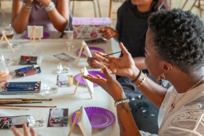 People painting at a table with art supplies.