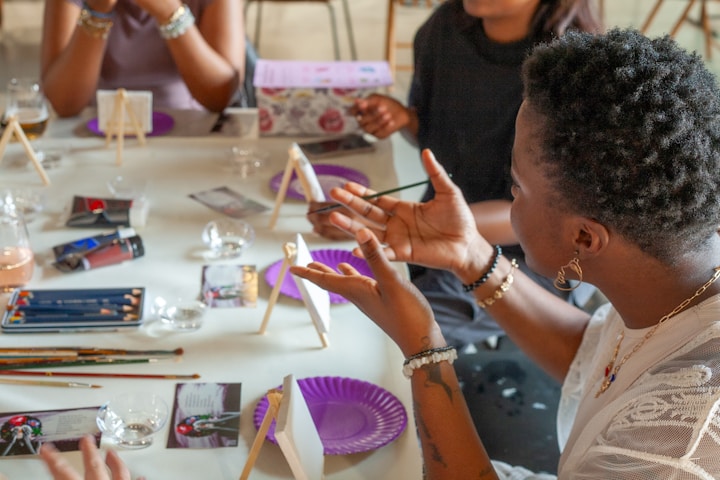 People painting at a table with art supplies.