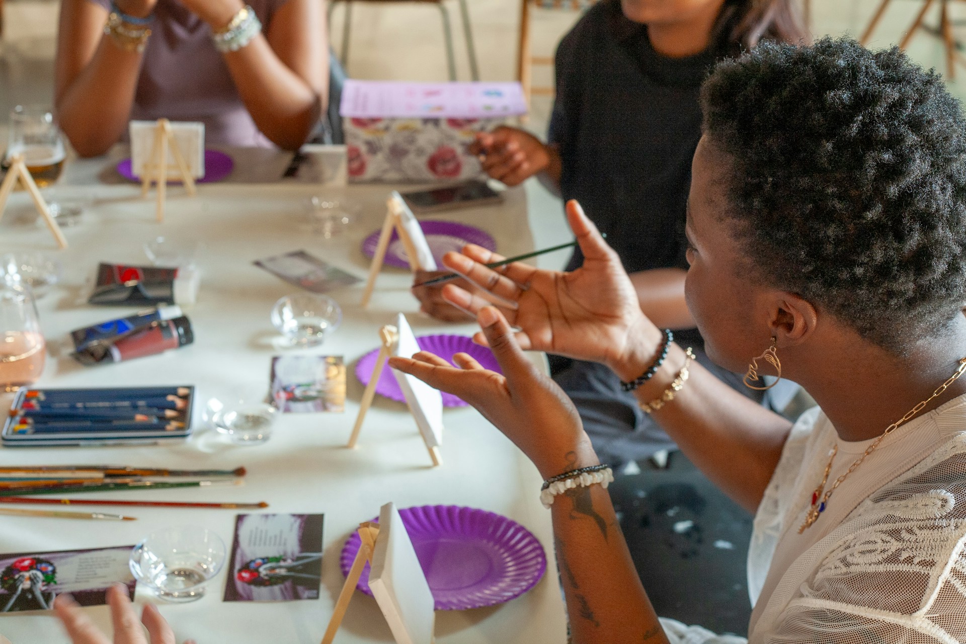 People painting at a table with art supplies.