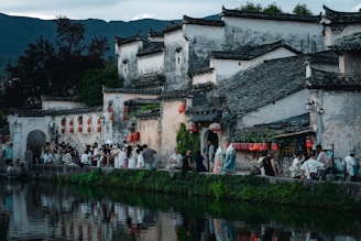 Traditional chinese village with people by the water.