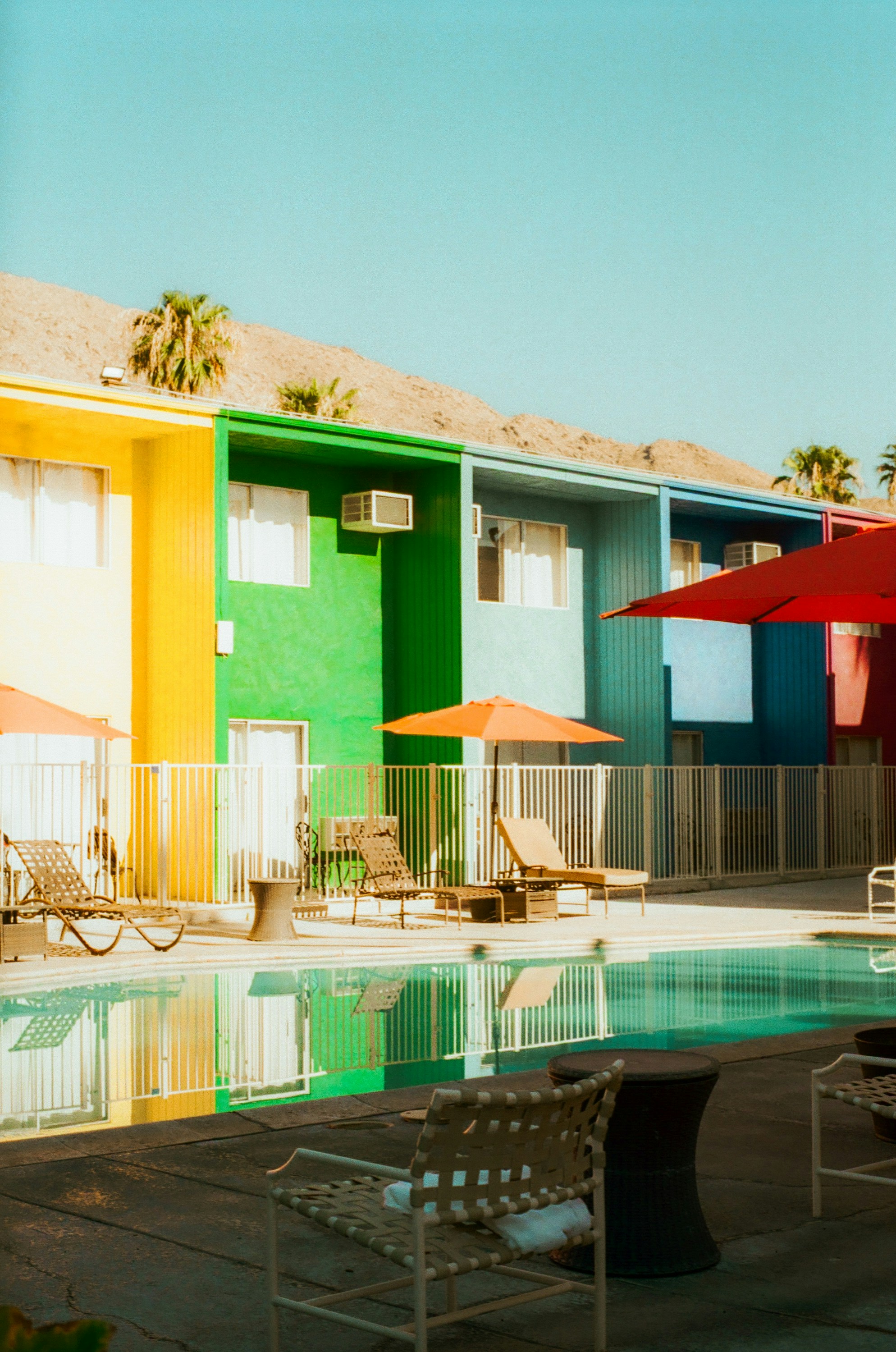 Colorful buildings beside a swimming pool with lounge chairs.