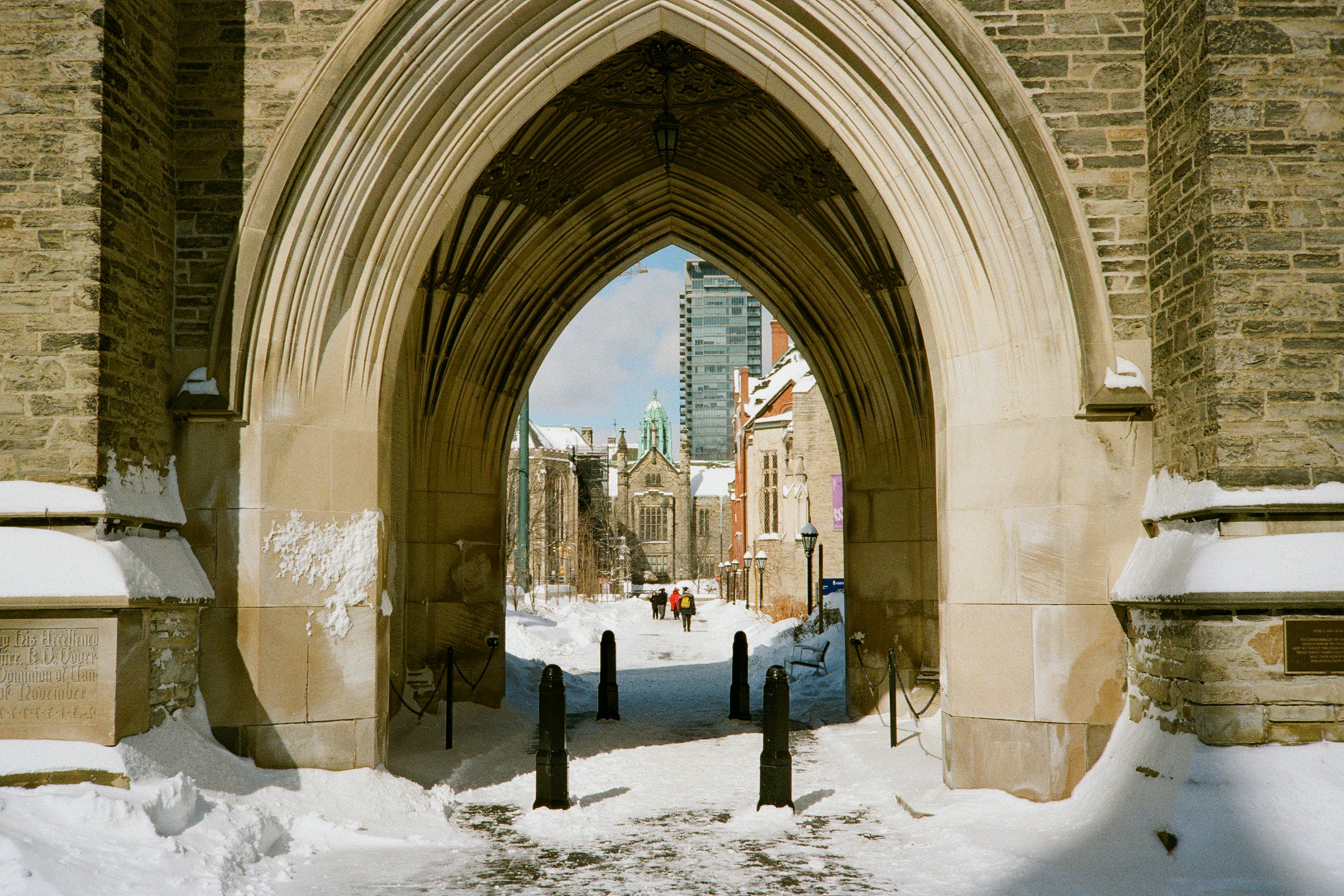 Snowy archway leading to a historic building complex.