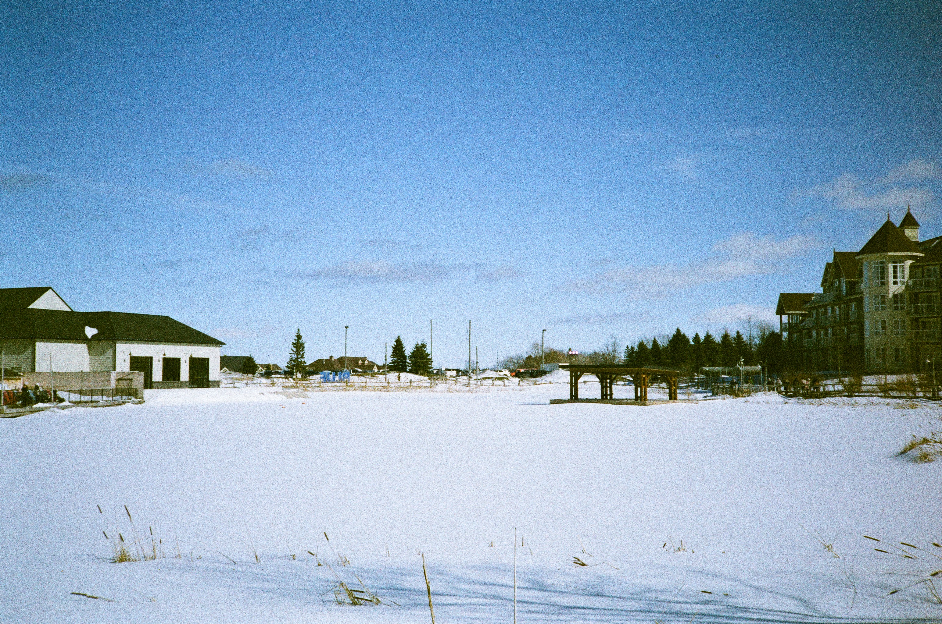 Snowy landscape with buildings under a clear blue sky.