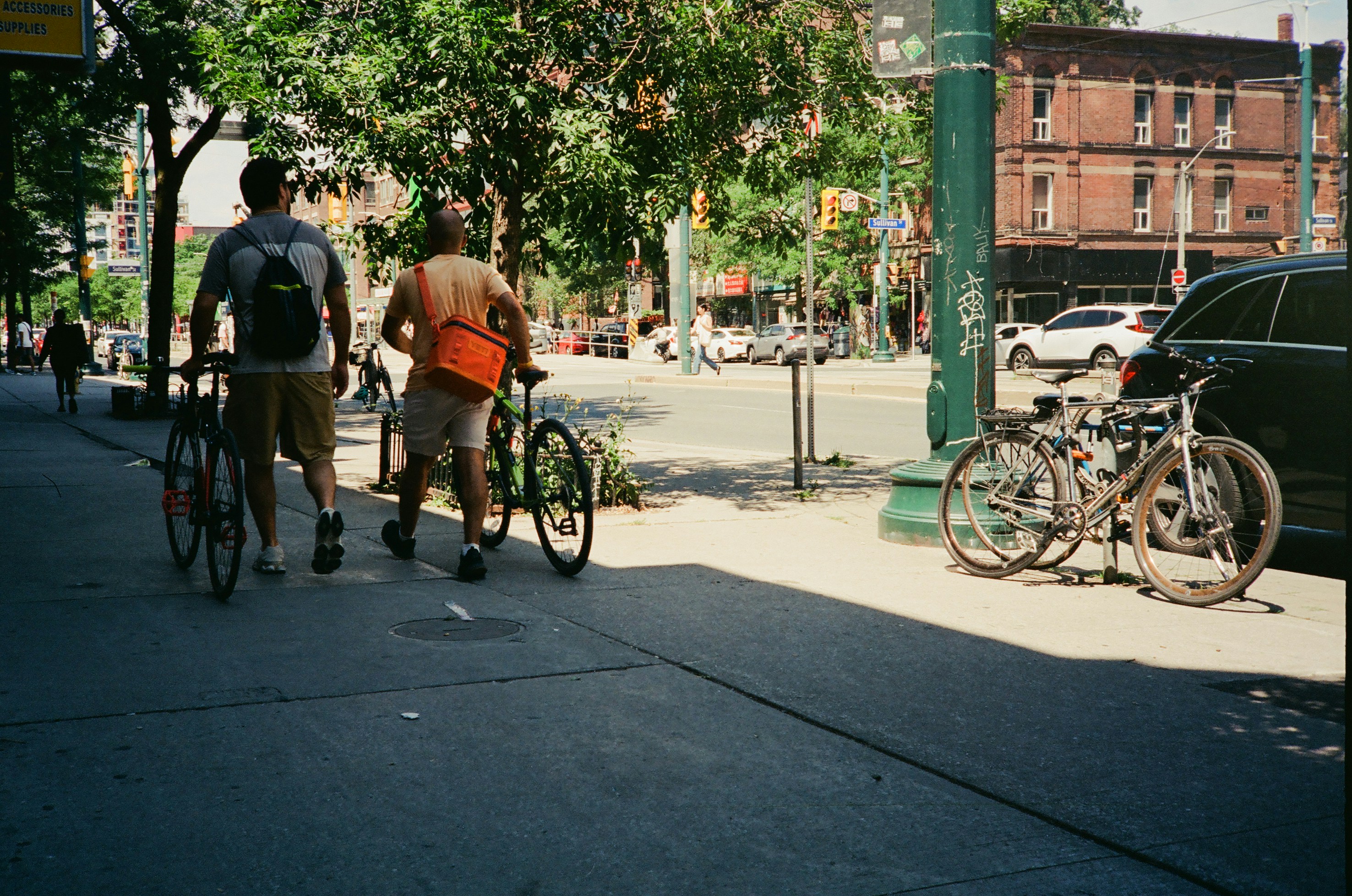 Two people walk bicycles down a city street.