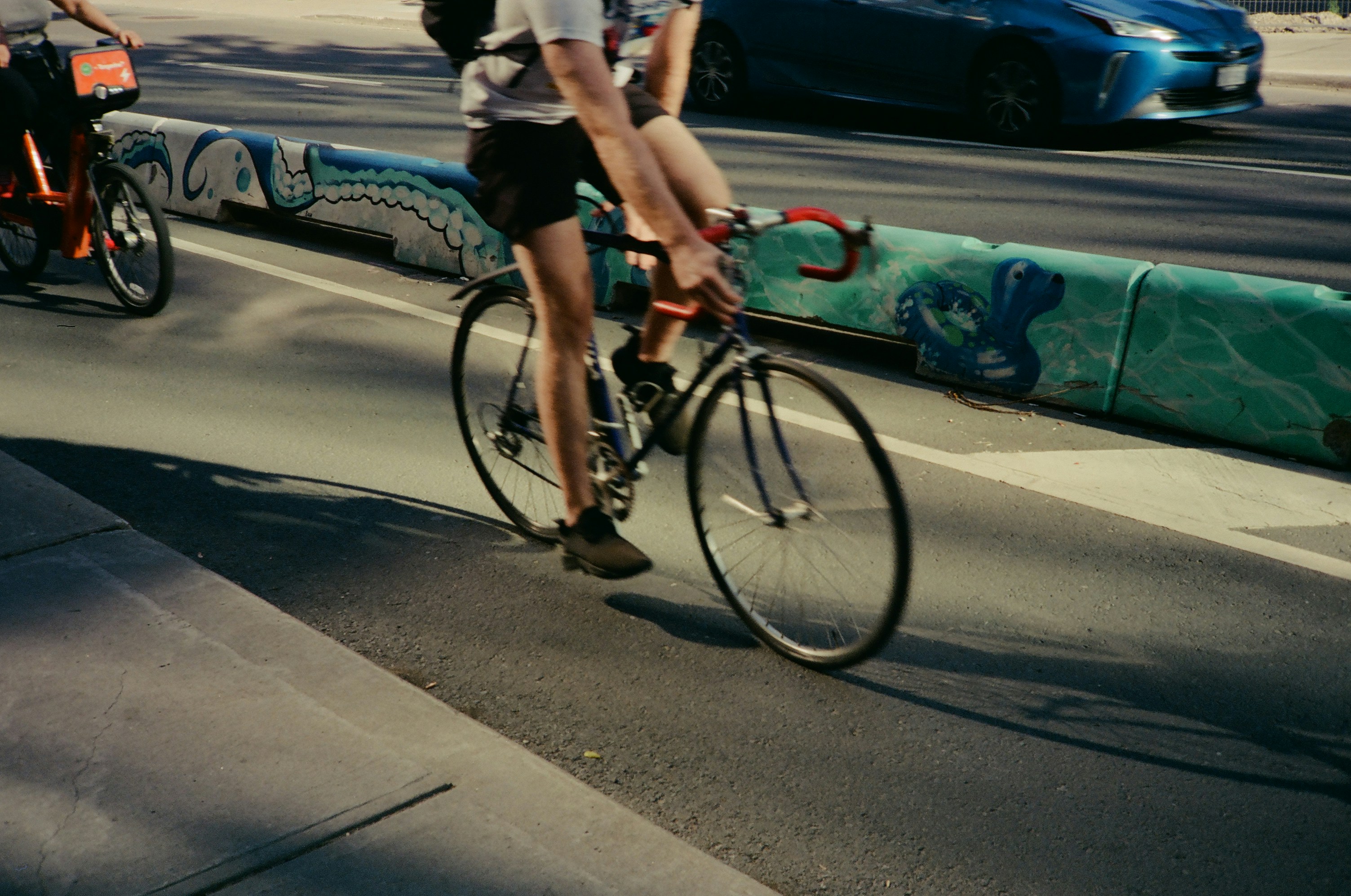 A person rides a bicycle on a sunny street.