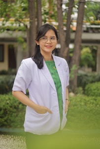 A woman in a lab coat smiles outdoors.