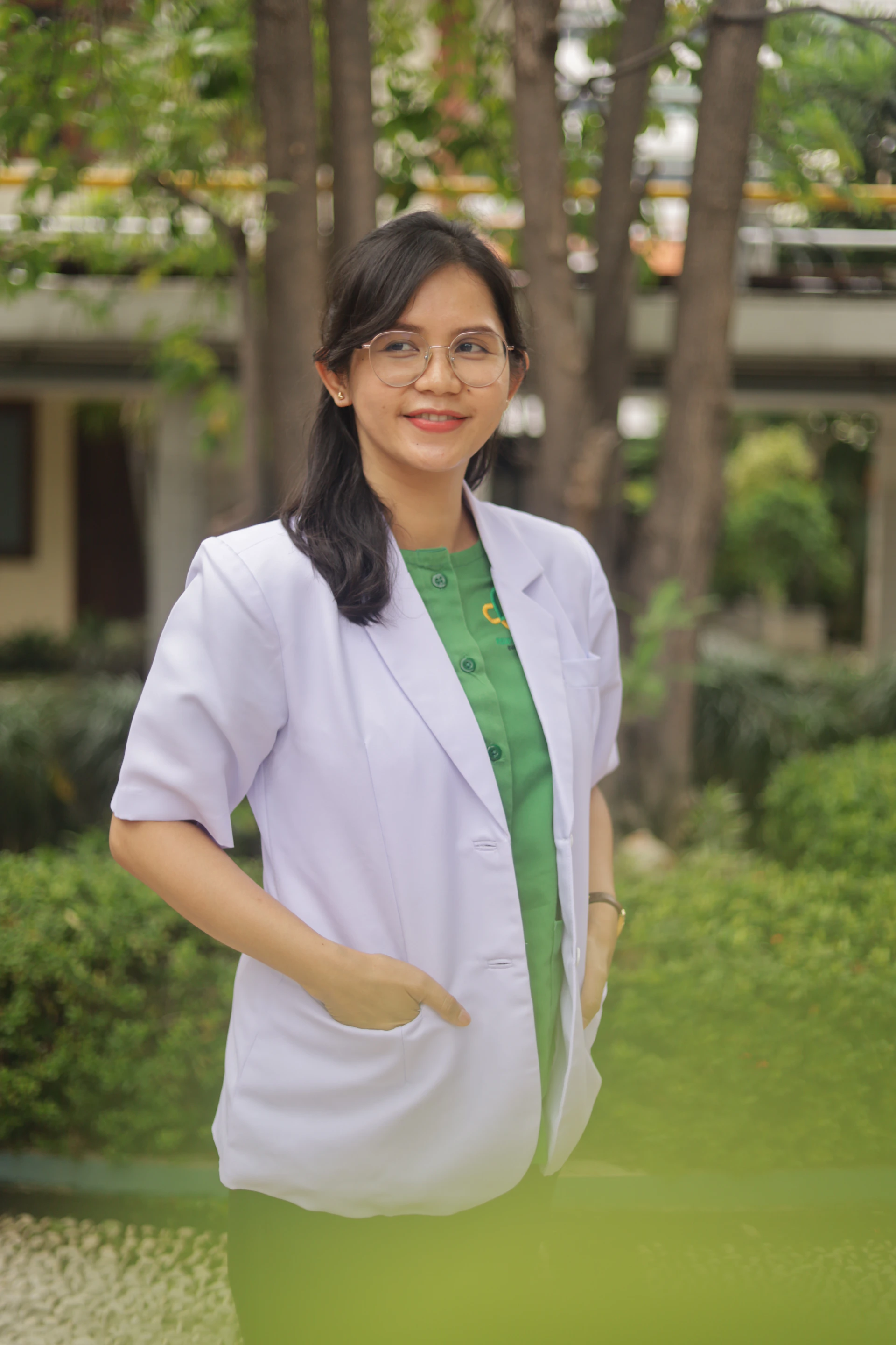 A woman in a lab coat smiles outdoors.