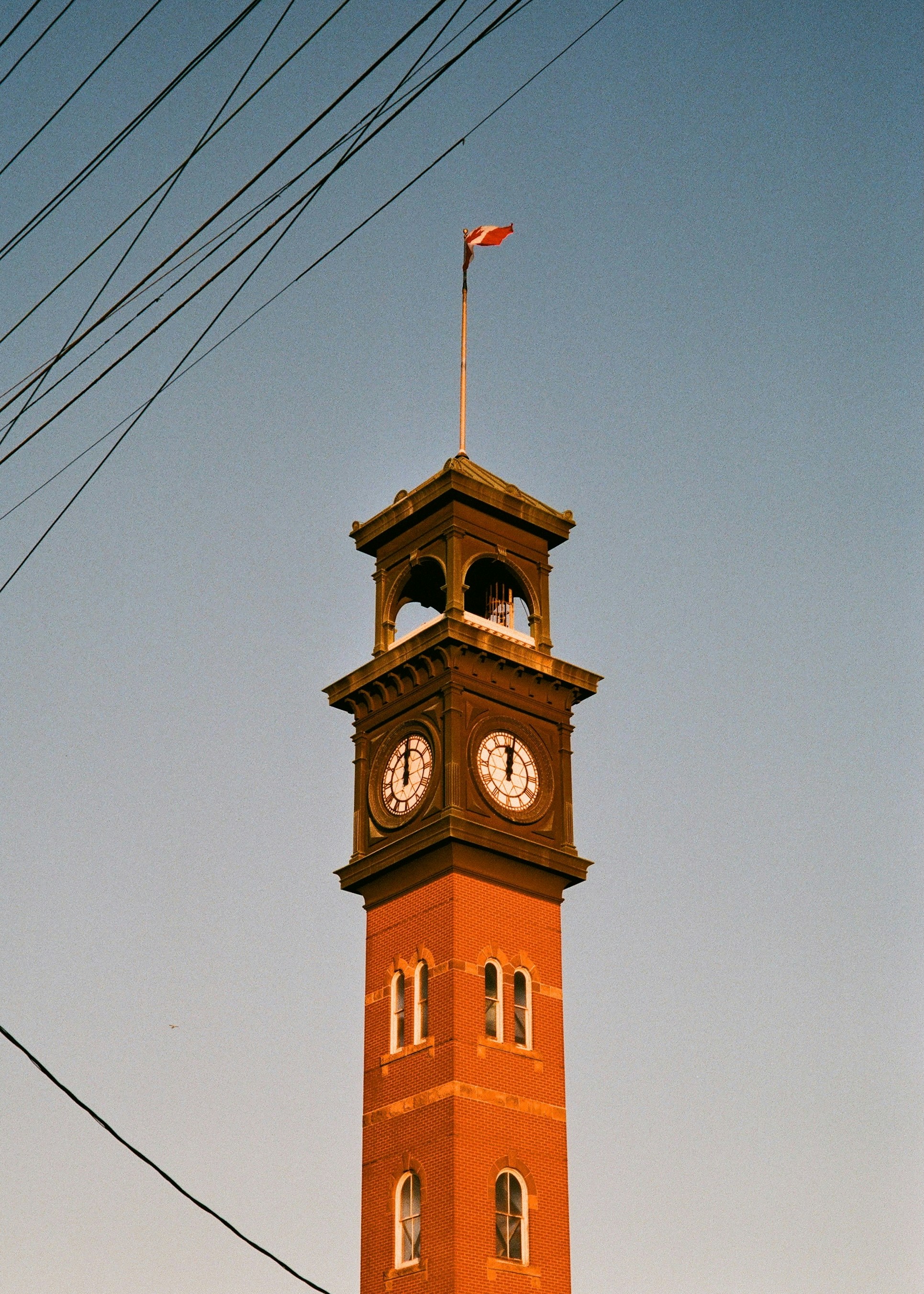 Orange clock tower with a flag against blue sky