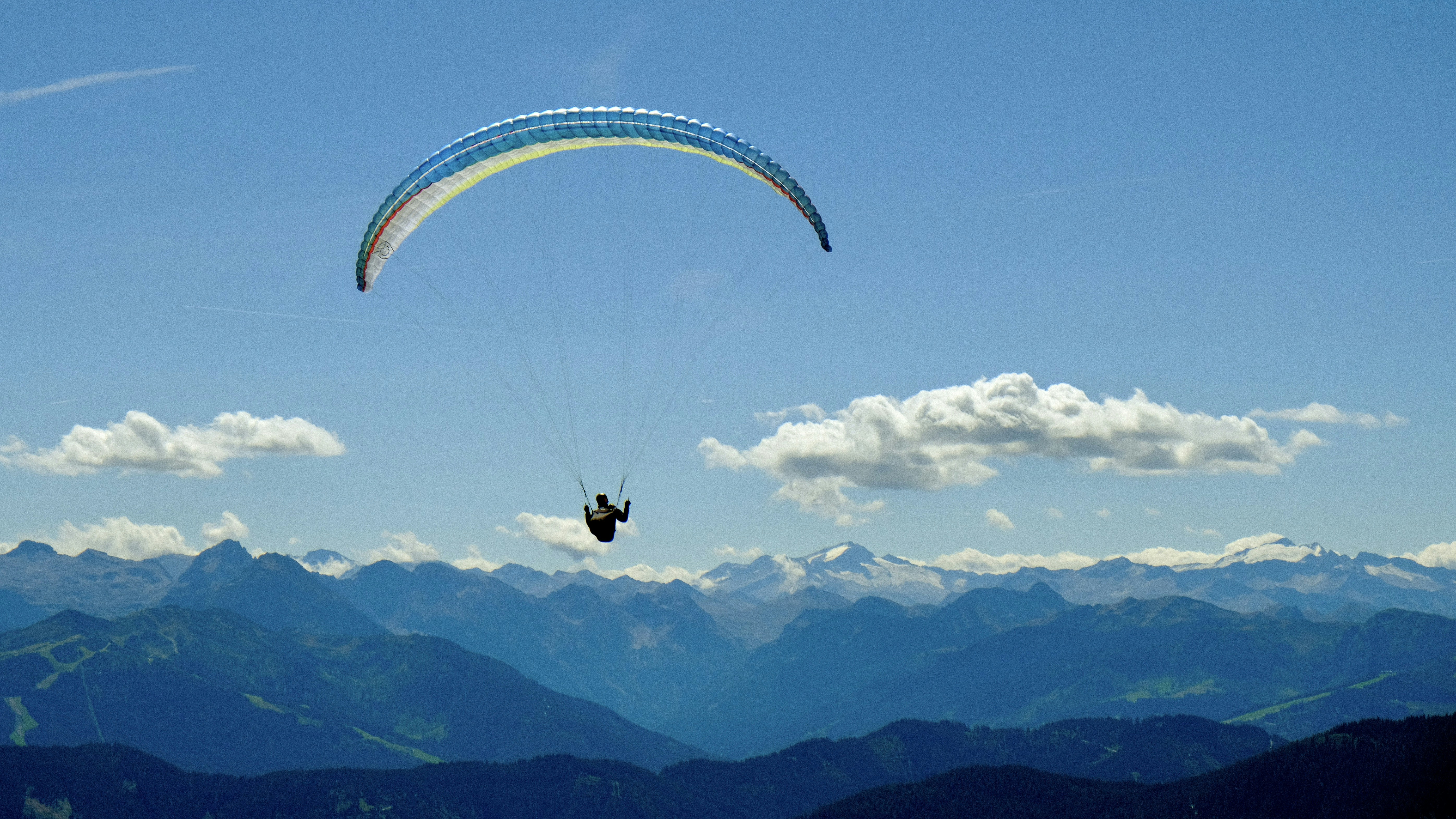 Gleitschirm schwebt unter blauem Himmel über majestätische Berge