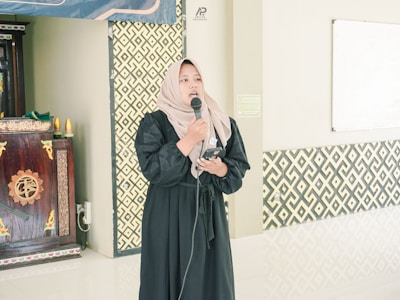 A woman in a hijab speaks into a microphone.