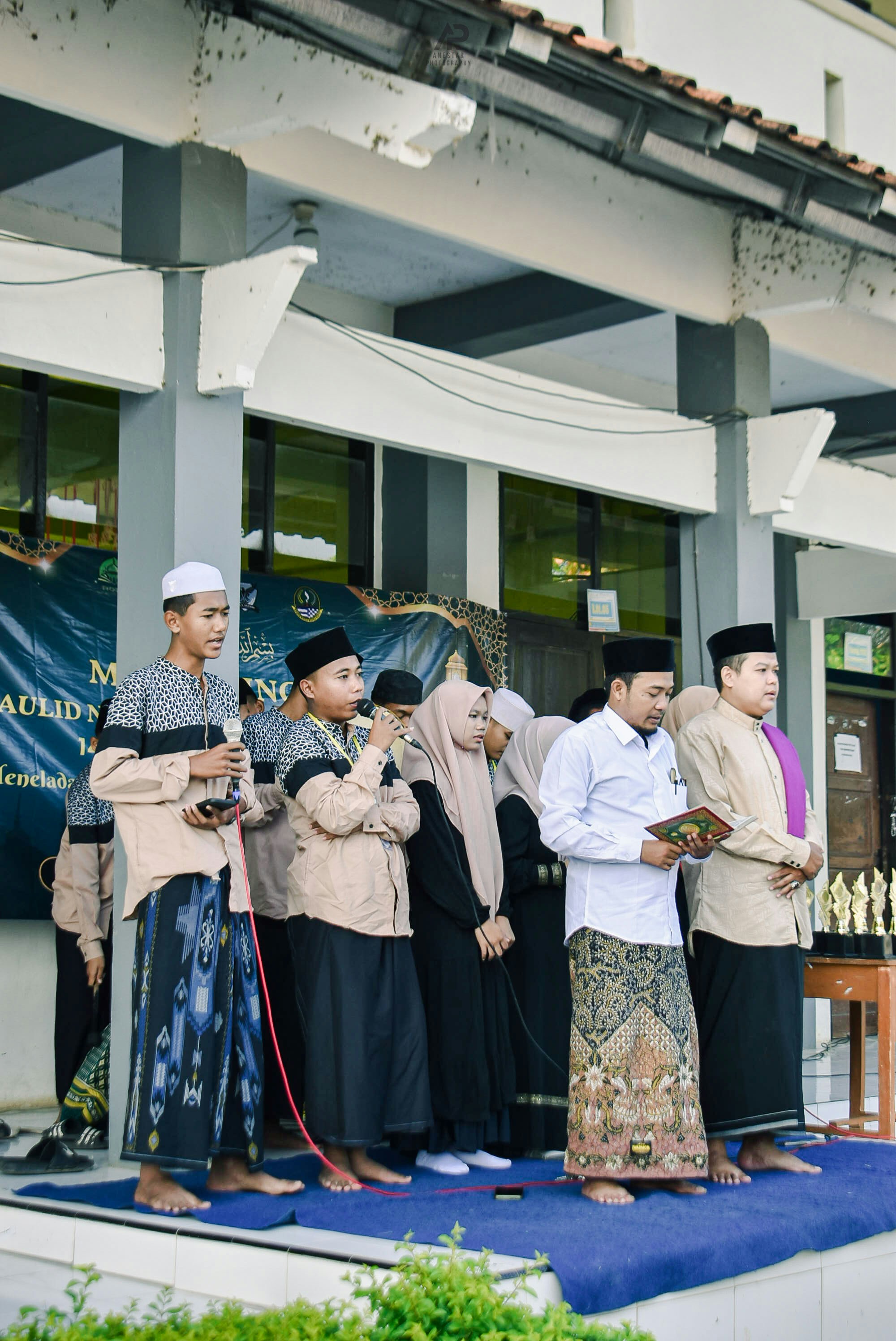 A group of men and boys stand on a stage.