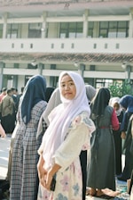 Young woman in hijab smiles in front of building