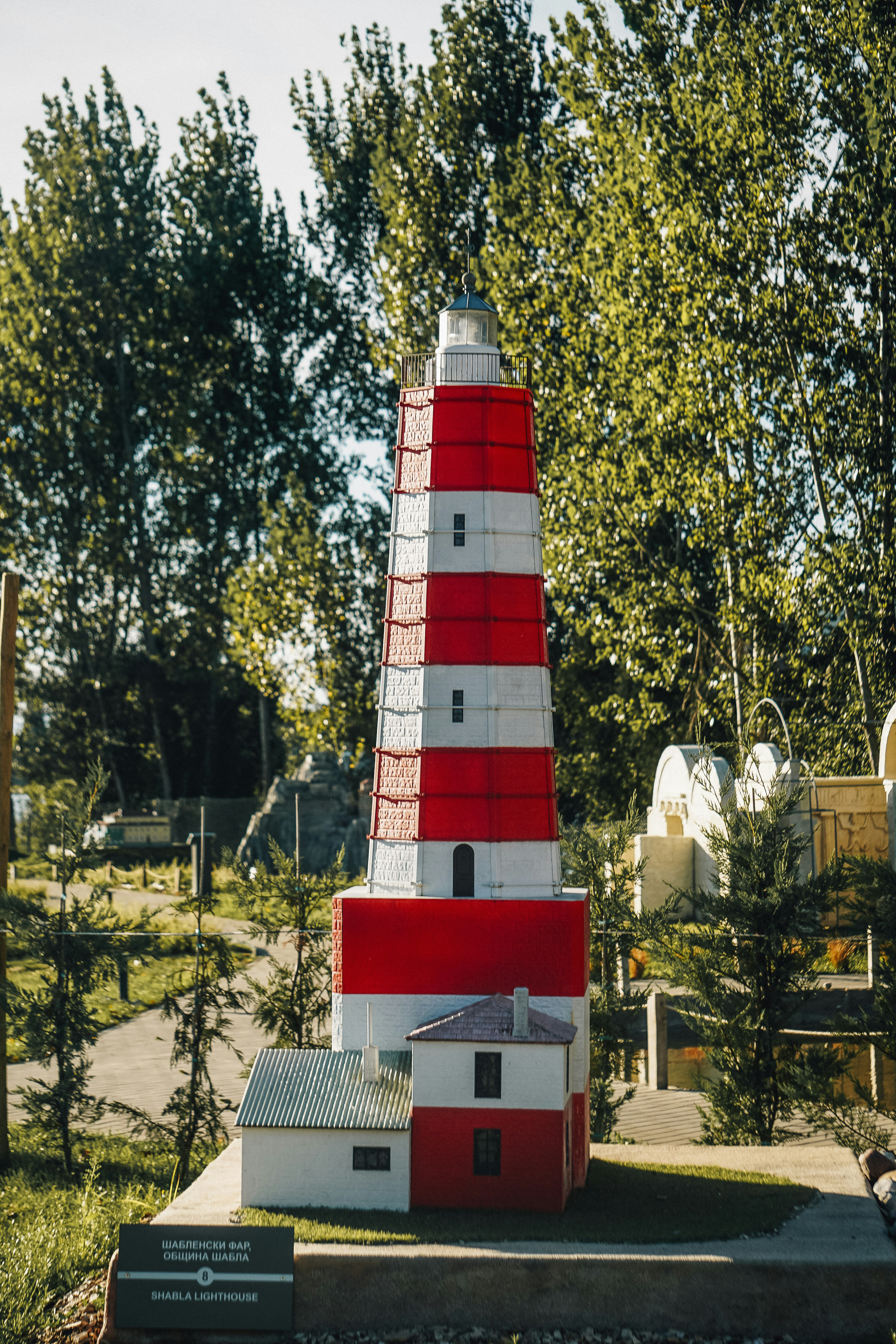 A miniature red and white striped lighthouse with buildings.