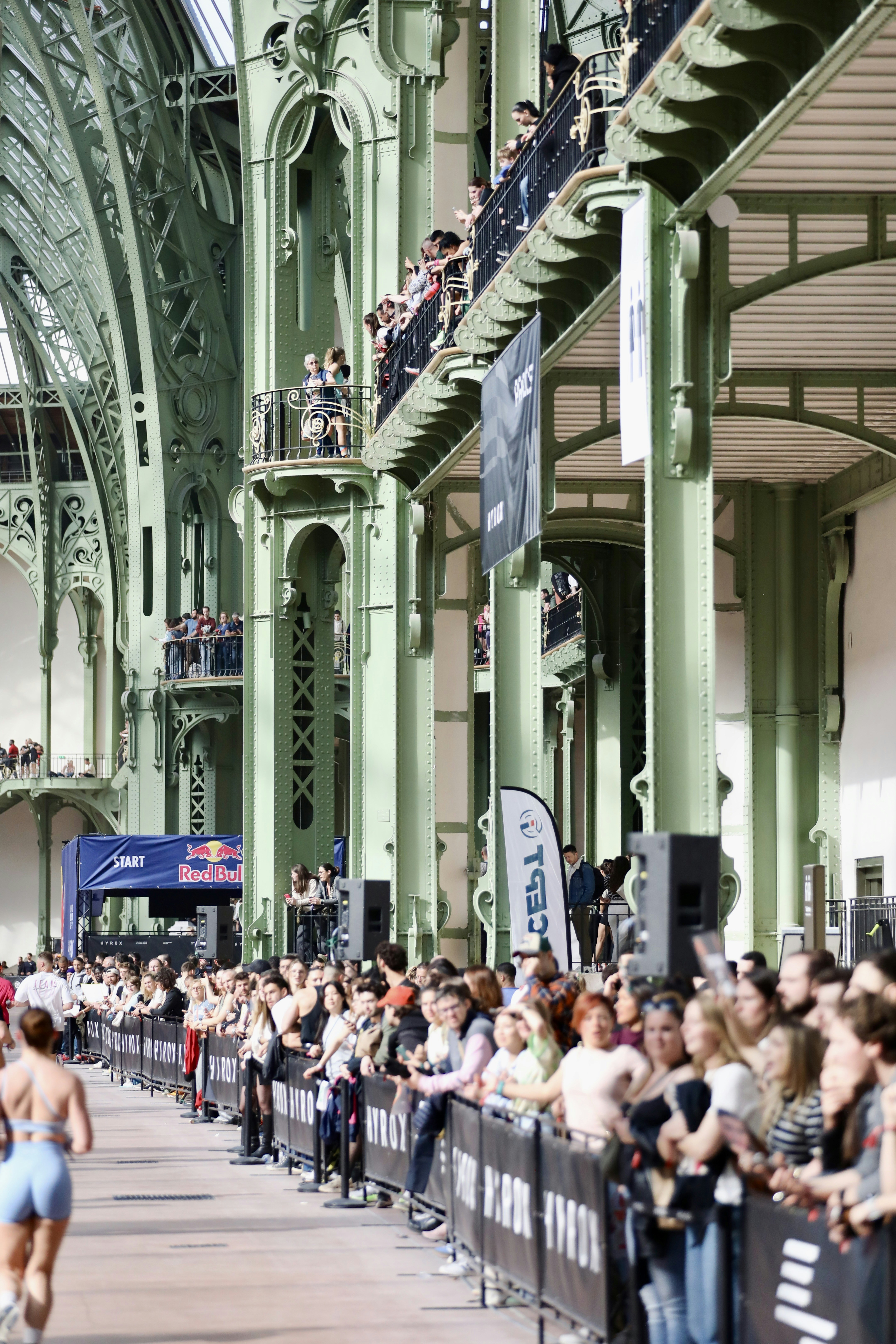 Crowd watches athletes compete in a large indoor venue.
