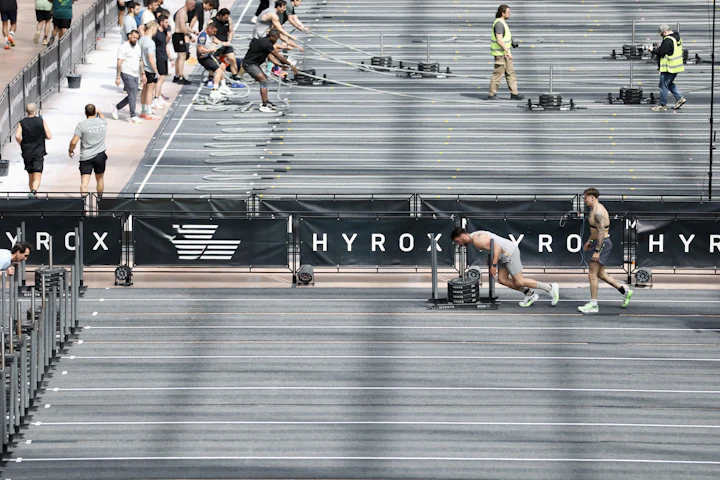 Prova de Hyrox em arena, atleta empurrando trenó