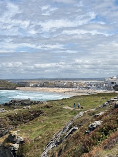 Coastal town with beach and rocky foreground under clouds