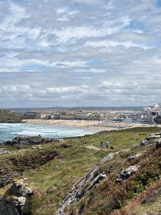 Coastal town with beach and rocky foreground under clouds