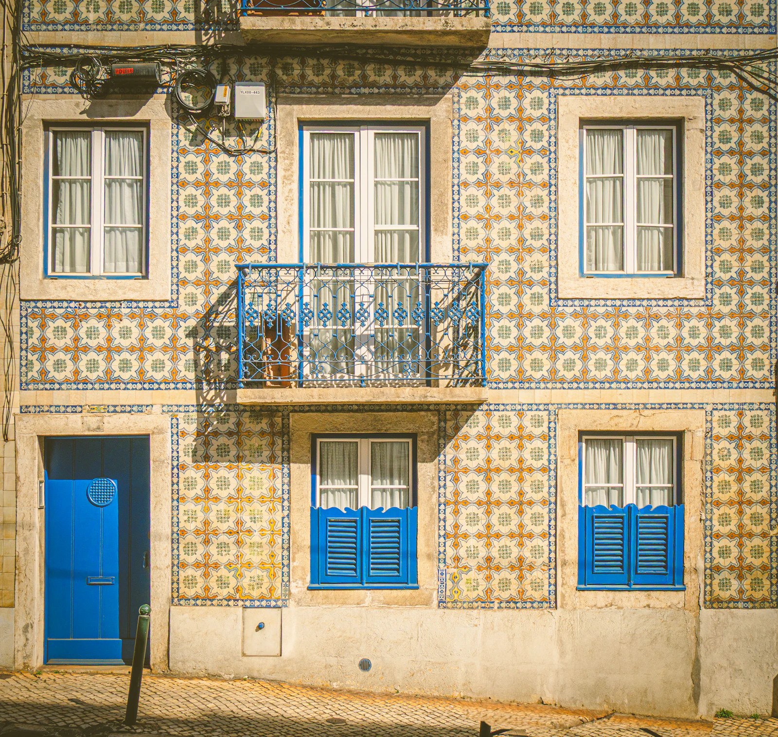 Ornate azulejo-tiled facade with a blue door and shutters in Lisbon