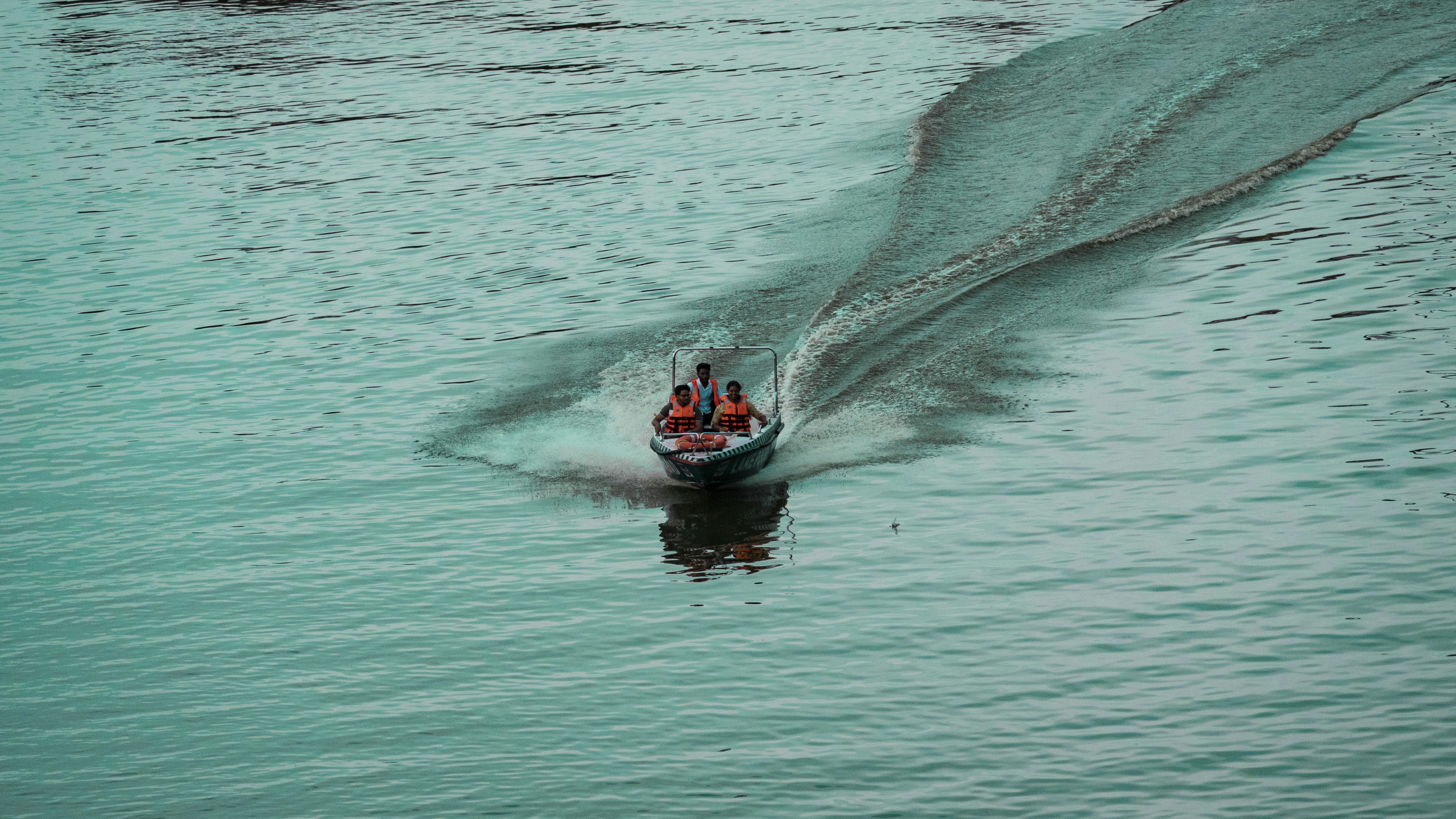Small boat with people speeds across turquoise water