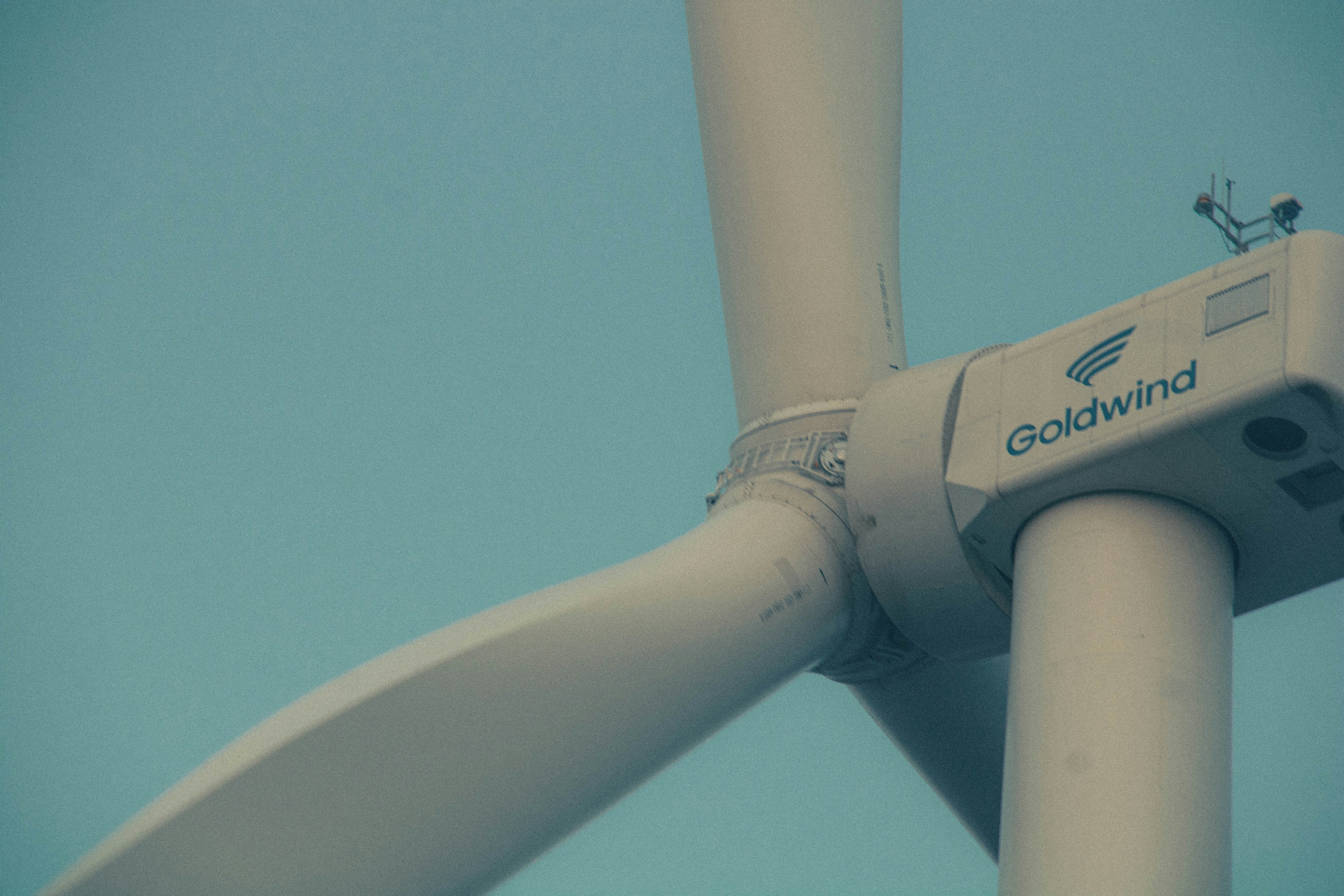 Close-up of a white wind turbine against blue sky