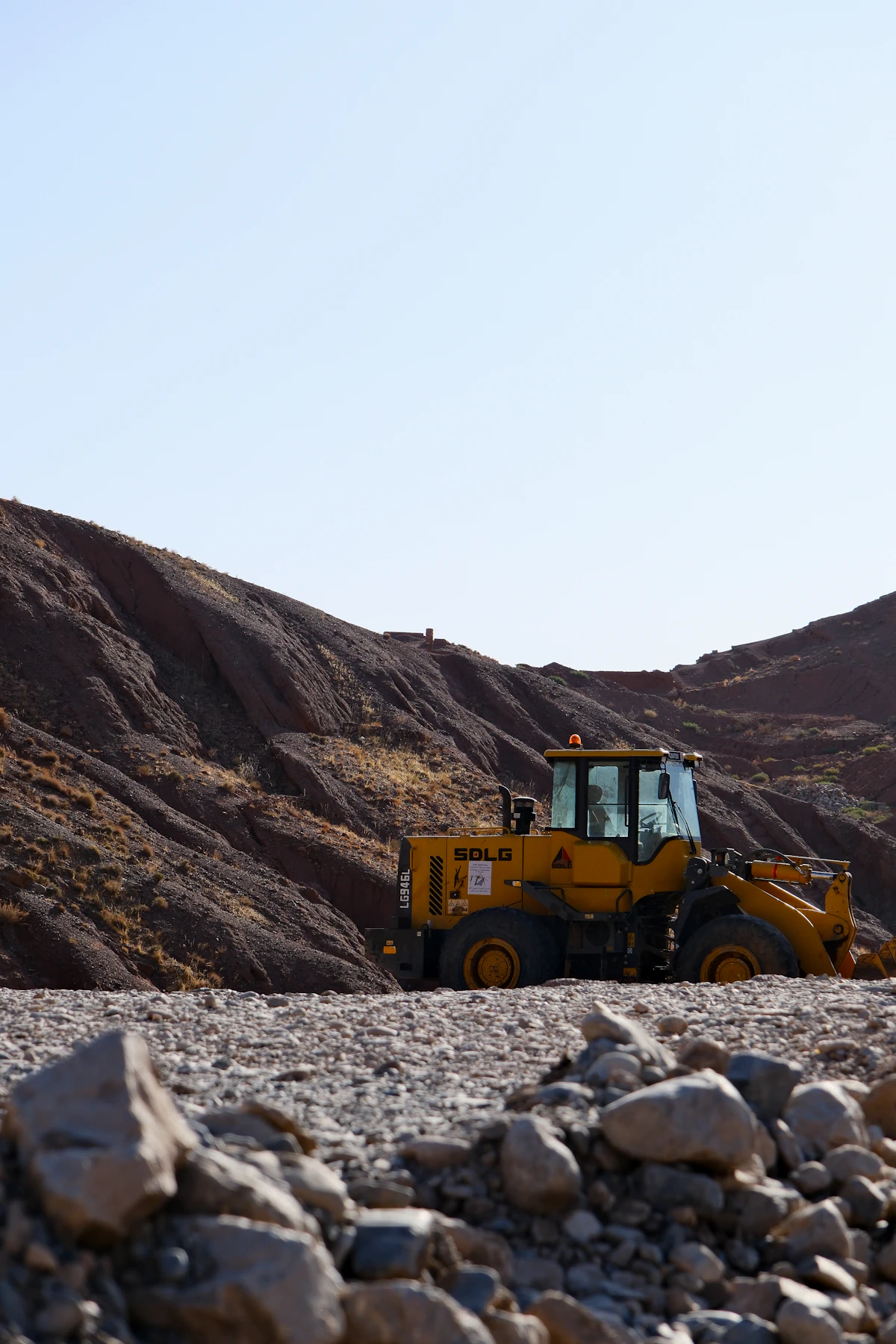 A yellow bulldozer parked at a construction site with hills in the background